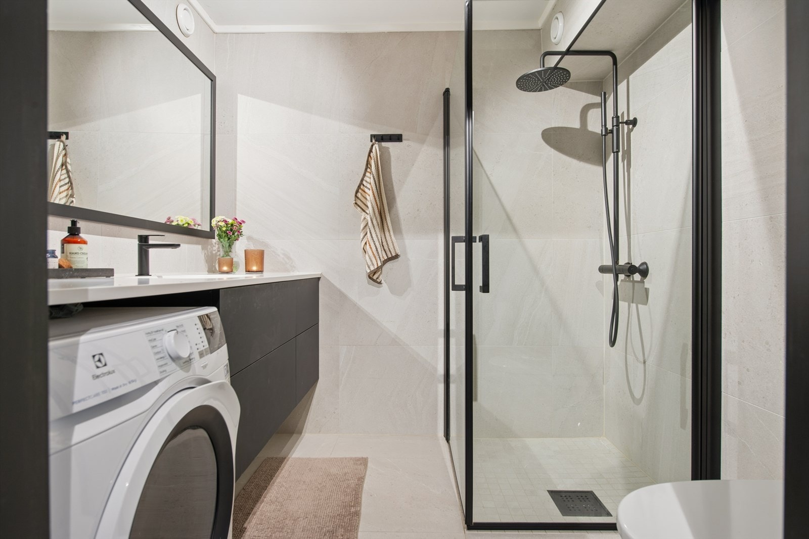 Badet er utstyrt med toalett, dusjhjørne med glassvegger og baderomsinnrending med servant og speil. Her er det også opplegg for vaskemaskin. Galleribilde
