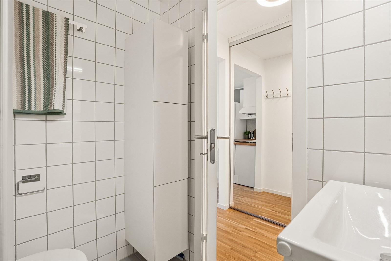 Badet har flislagt gulv med behagelig varme og et praktisk høyskap for ekstra oppbevaring. Galleribilde