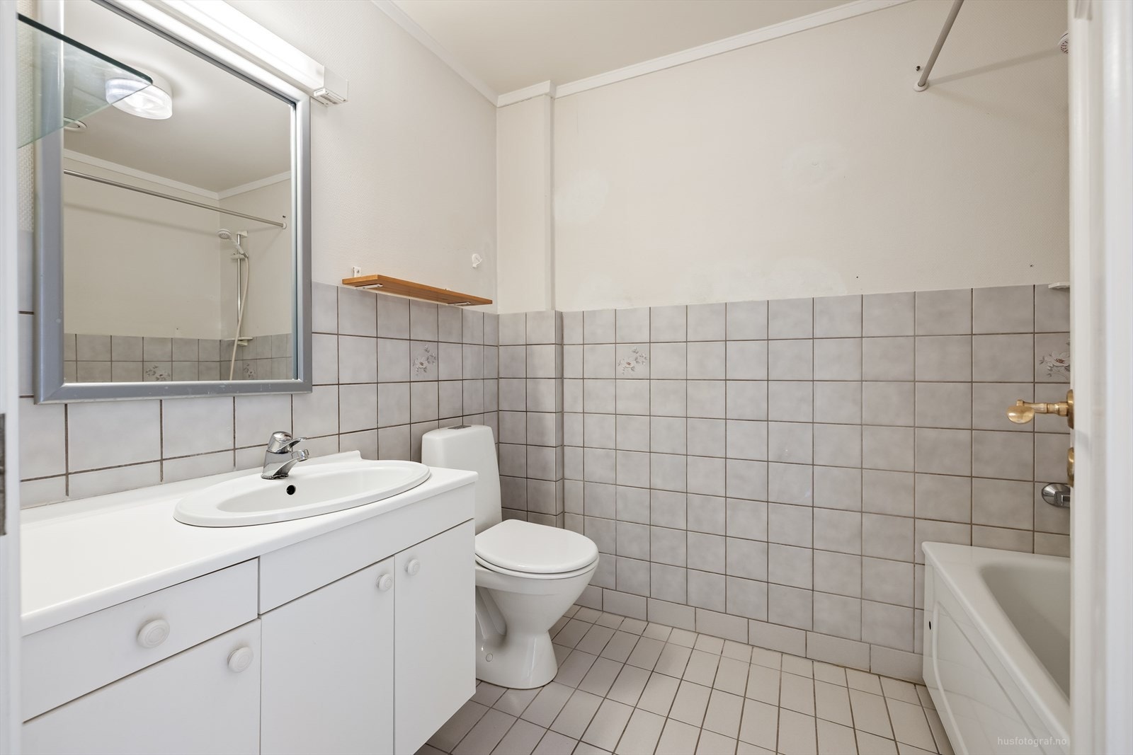 Flislagt bad utstyrt med servantinnredning, toalett og badekar. Galleribilde
