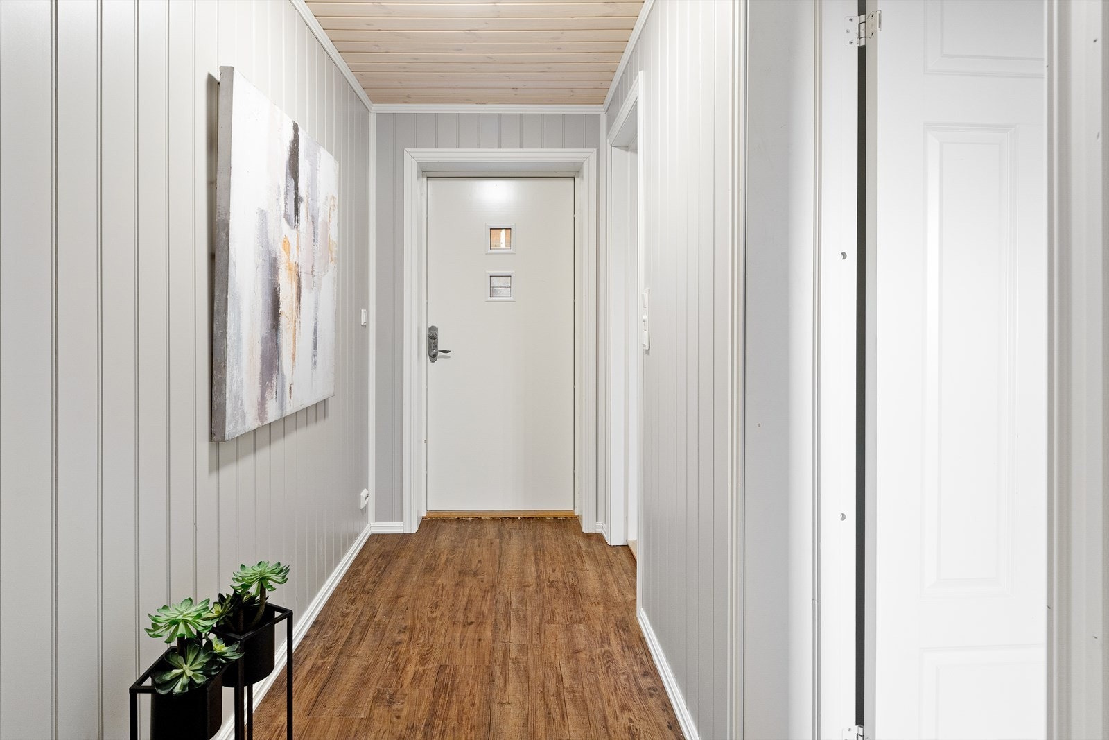 Overflatene i entréen består av malte panelplater og parkettgulv, som gir et praktisk inngangsparti. Galleribilde