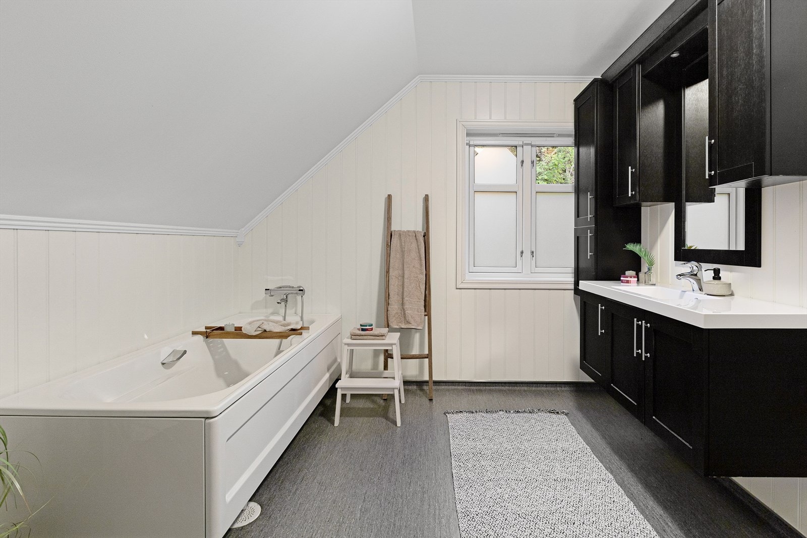 Badet i andre etasje har gulvbelegg og panelplater på veggene, med badekar og servant. Galleribilde