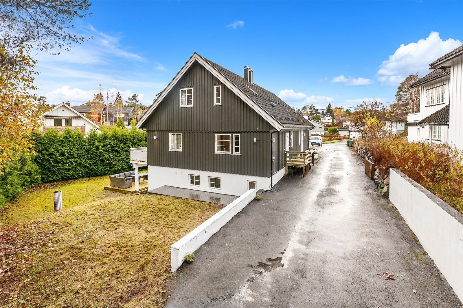 Asfaltert adkomstvei og gårdsplass samt en stor hage med hekk som gir lite innsyn. Galleribilde