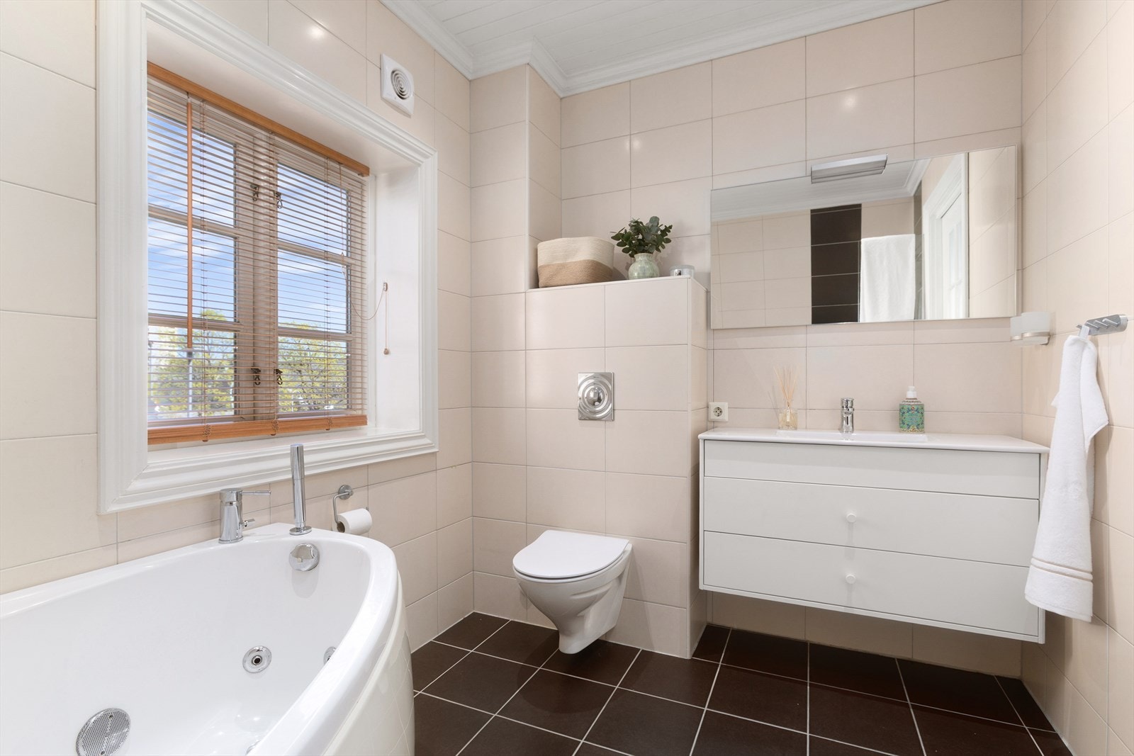 Badet er utstyrt med servant med underskap, speil, toalett, badekar og dusjnisje Galleribilde