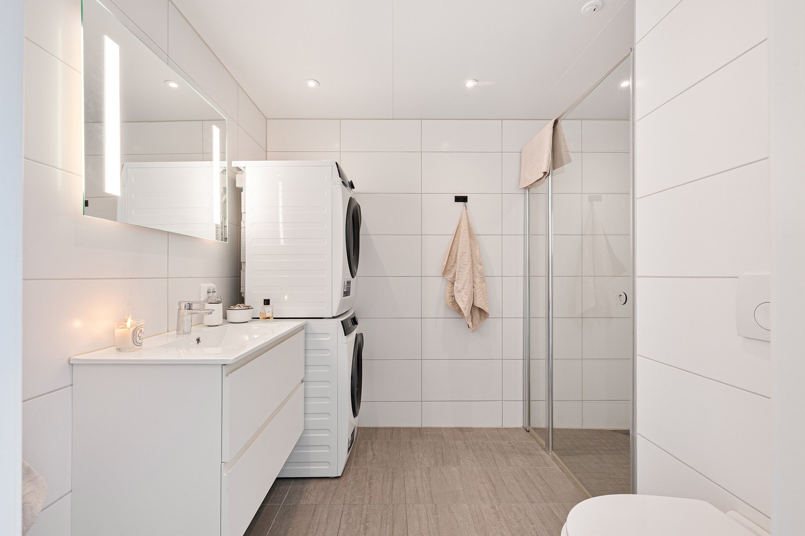 Badet er flott helfliset med fine fliser på gulv og på vegg. Det er spotter i tak som gjør badet ekstra lyst og det er i tillegg speil på vegg over servant med innfelt lys. Galleribilde