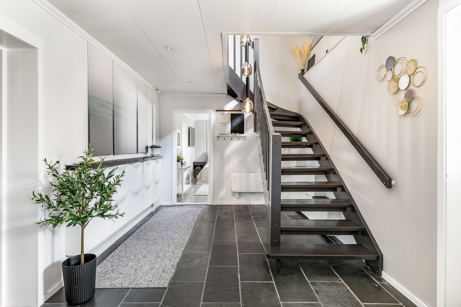 De fleste av underetasjens innredede rom er forbundet med dette, benyttet som entré. Også her er det varmekabler i gulvet, som for øvrig har en praktisk overflate av fliser. Galleribilde