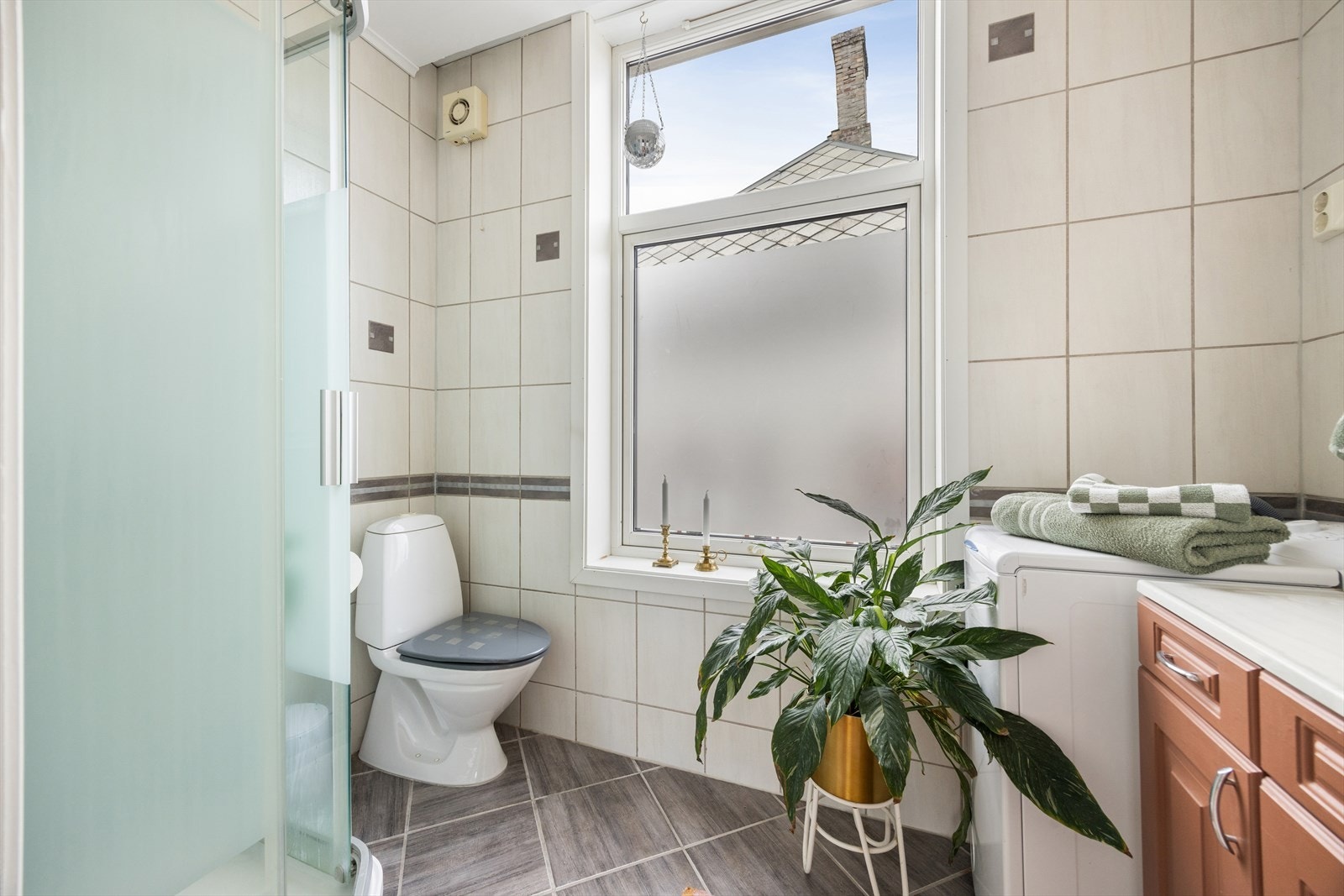 Badet er utstyrt med dusjkabinett, servantskap, toalett og opplegg for vaskemaskin. Galleribilde