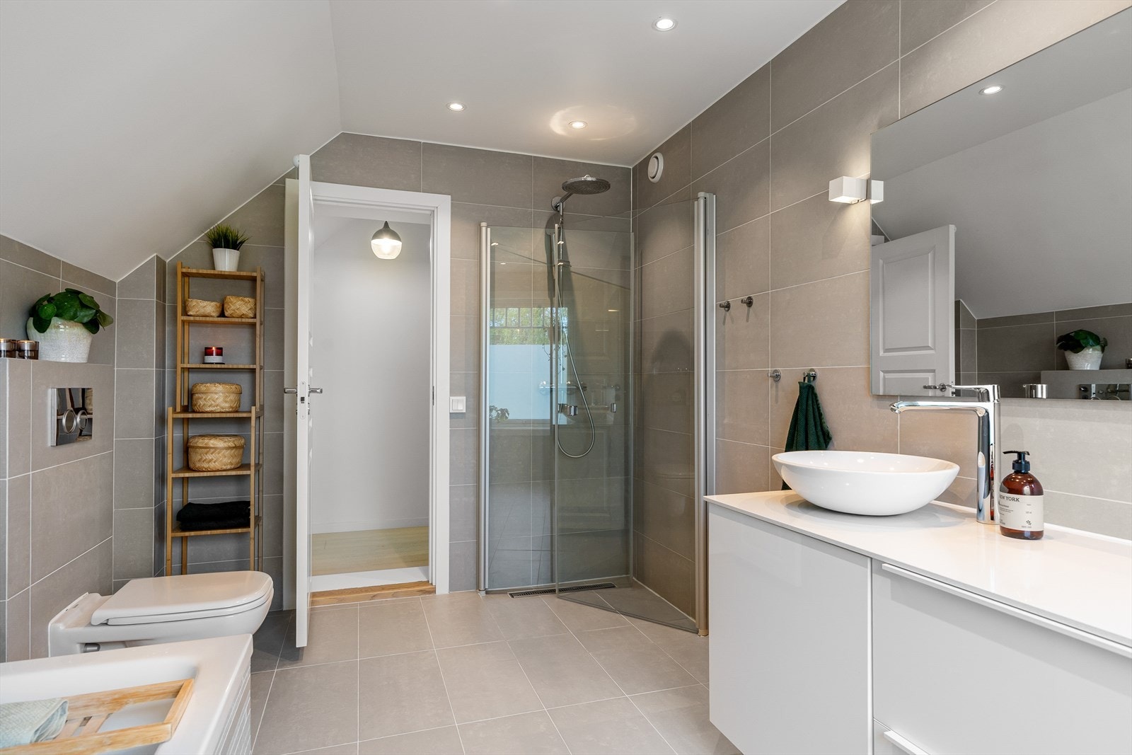 Badet er utstyrt med både mekanisk og naturlig avtrekk, badekar, dusj med innfellbare dører, vegghengt wc og servantskap med ettgreps blandebatteri fra Hansgrohe. Galleribilde
