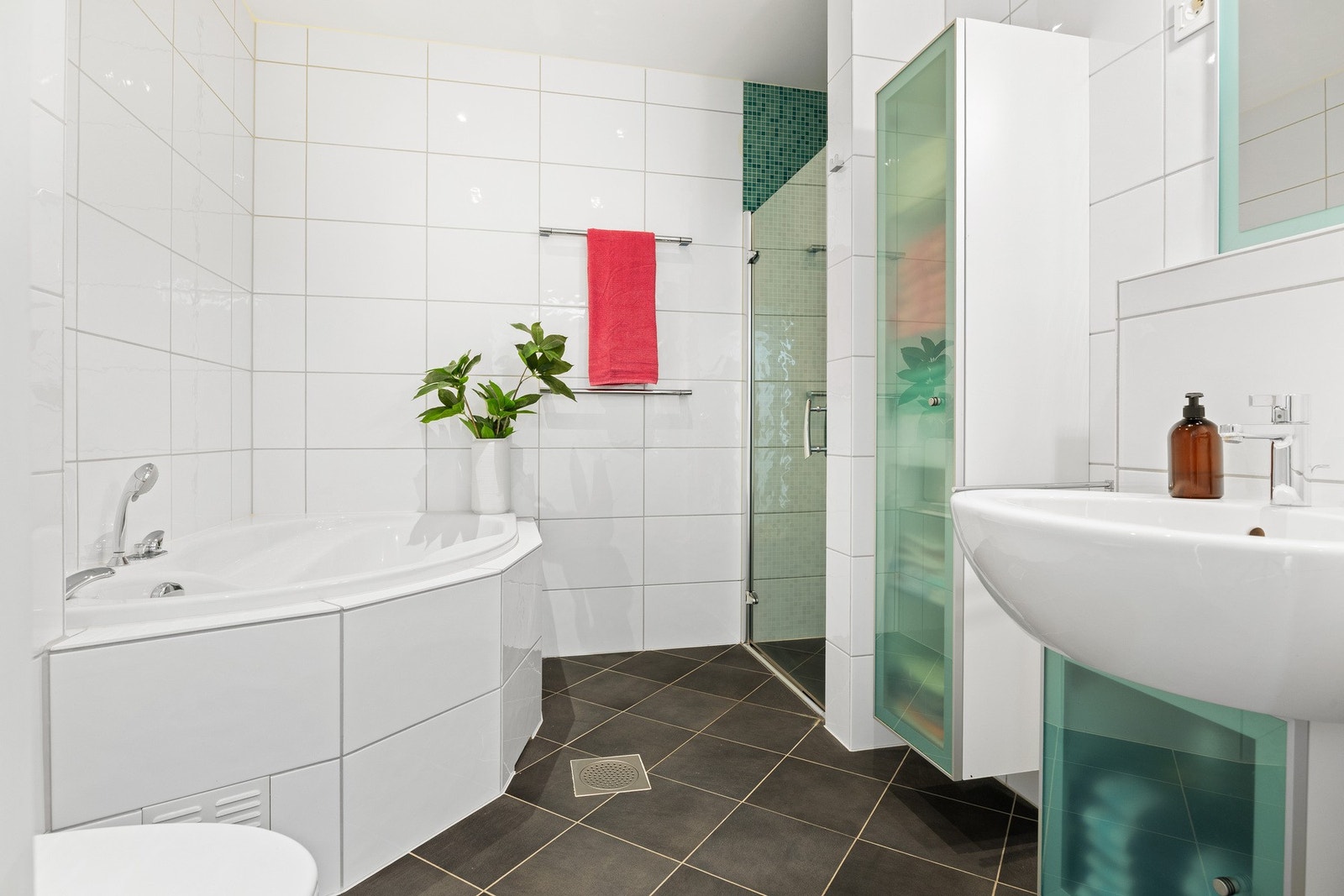 Badet i underetasjen er innredet med servant, dusjnisje, hjørnebadekar og klosett. Galleribilde