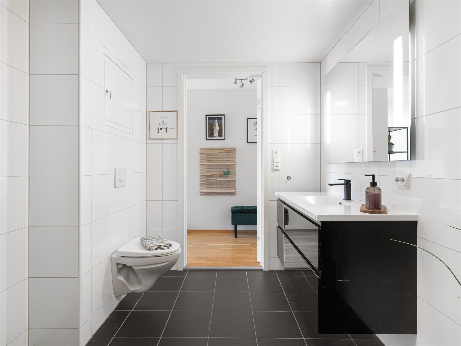 Badet er helfliset og utstyrt med veggmontert toalett og servant i moderne innredning. Galleribilde