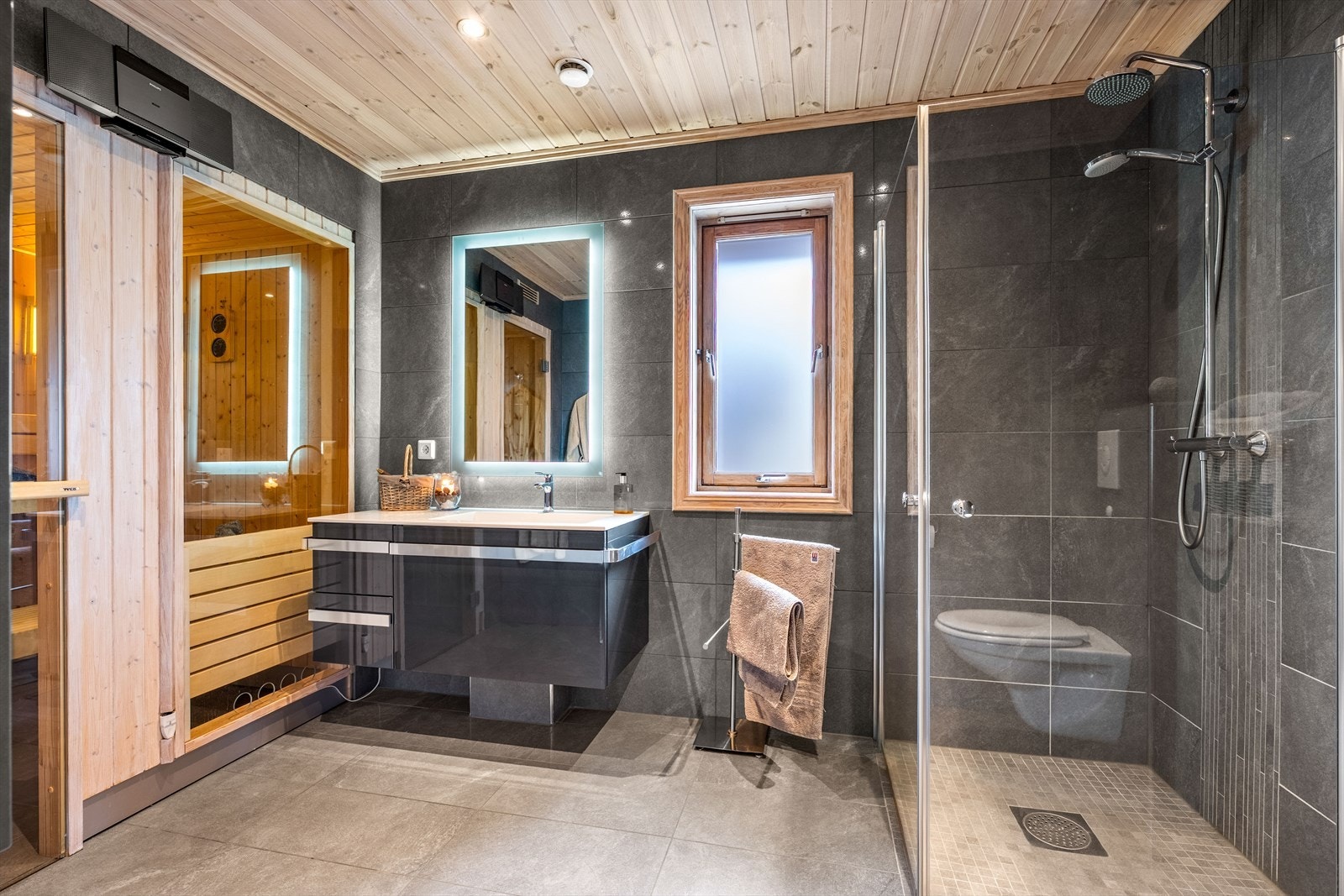 Badet er utstyrt med veggmontert toalett, dusjhjørne og en romslig servantinnredning. Galleribilde