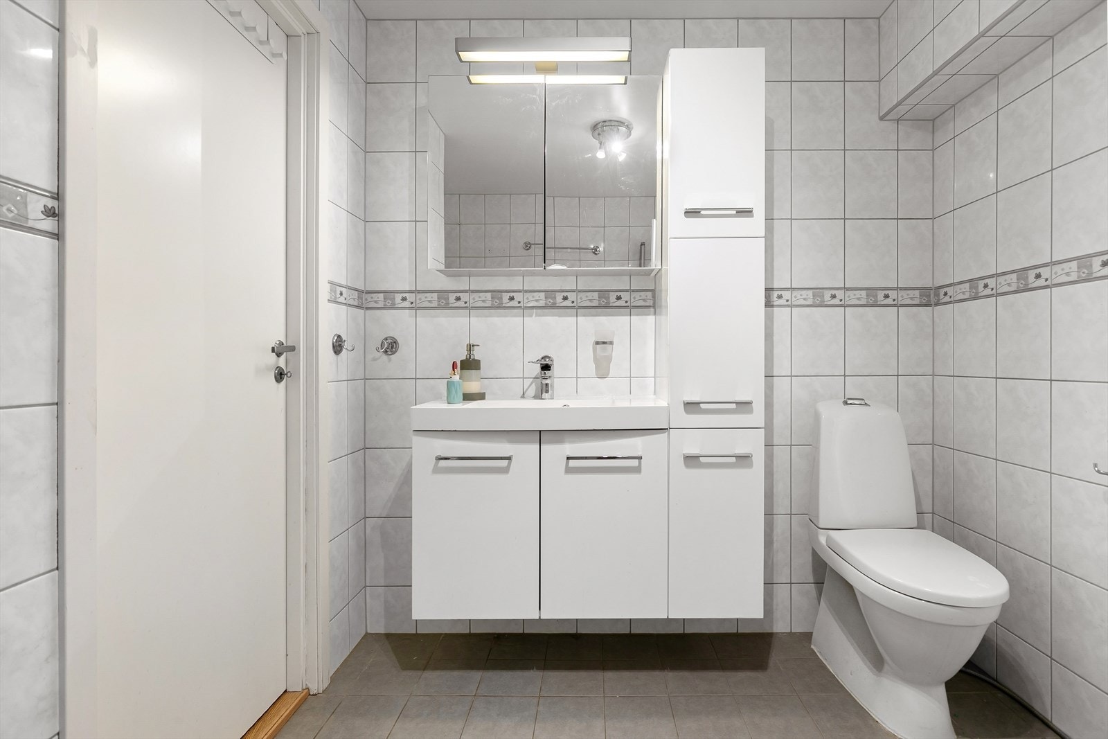 Badet har gulvmontert toalett og en romslig dusjsone med innfelte dusjdører i herdet glass. Det er opplegg for vaskemaskin Galleribilde