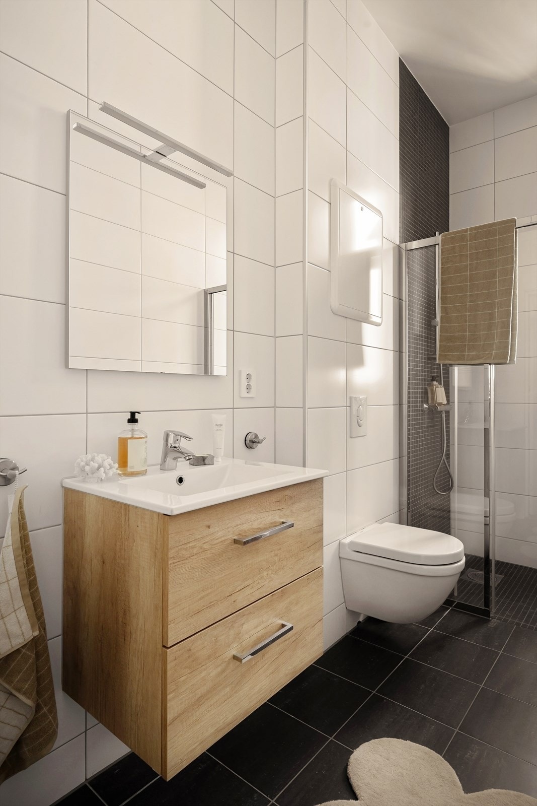 Badet er innredet med en 60 cm bred servantskap, vegghengt toalett og speil med belysning. Galleribilde