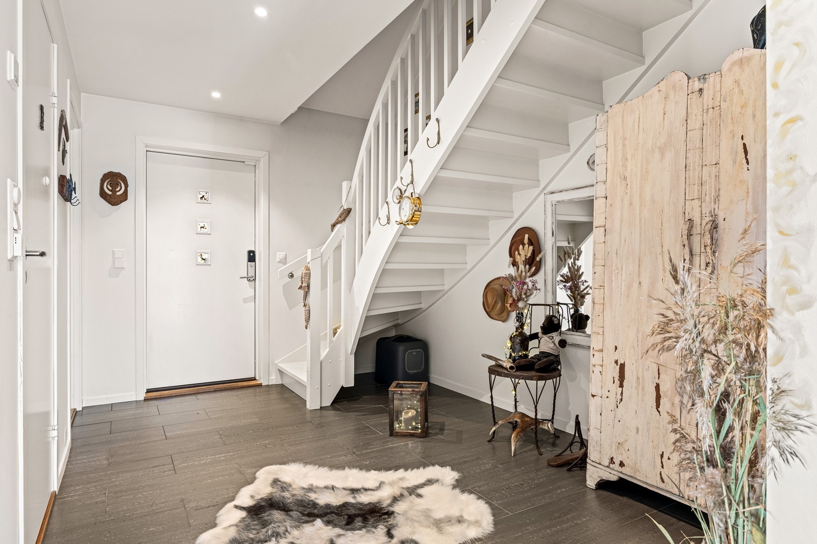Hallen har flislagt gulv og en malt tretrapp som fører opp til andre etasje. Galleribilde