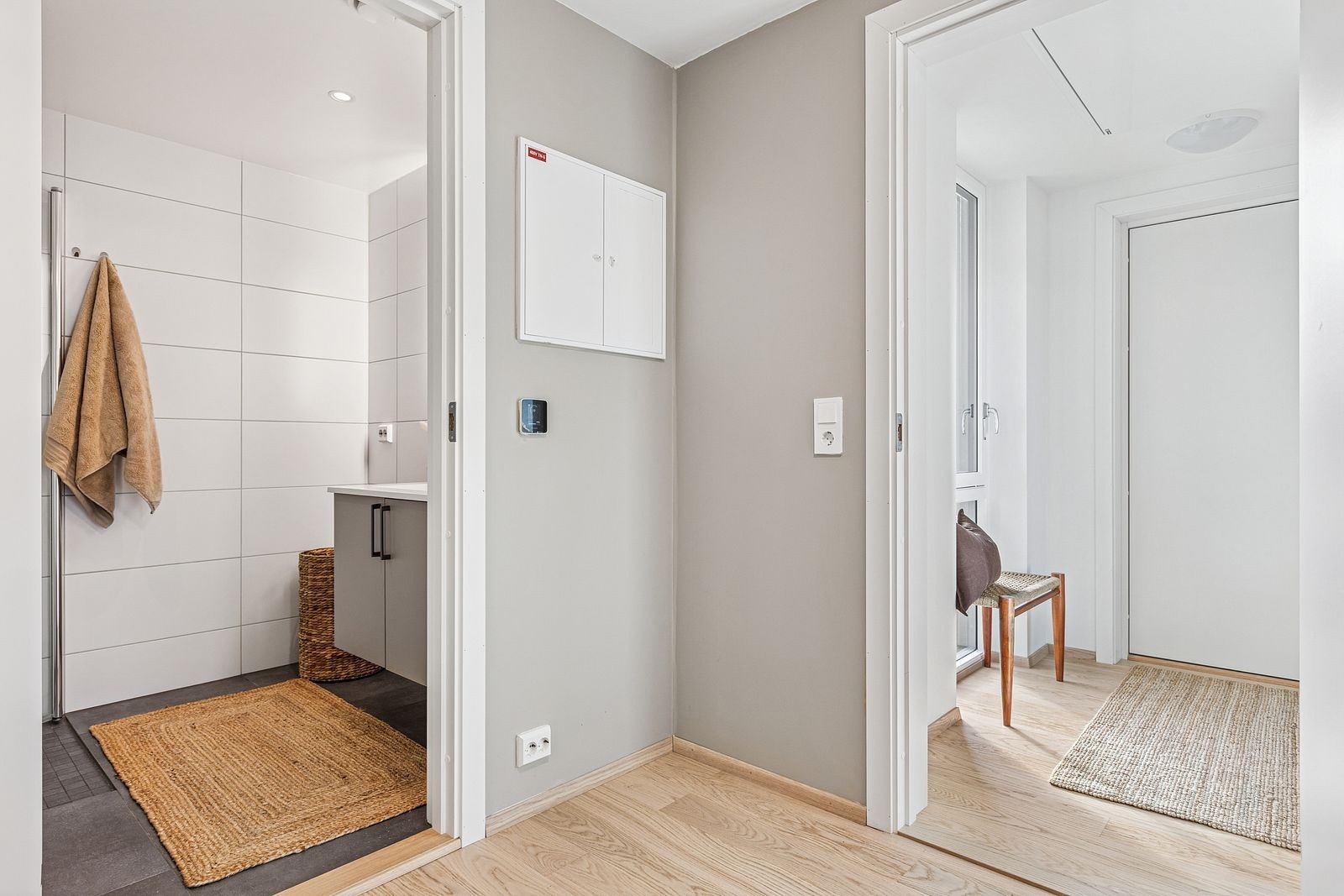 Videre fra badet har man boligens entré. Gjennomgående gulv skaper en helhetlig og sømløs overgang mellom rommene. Galleribilde