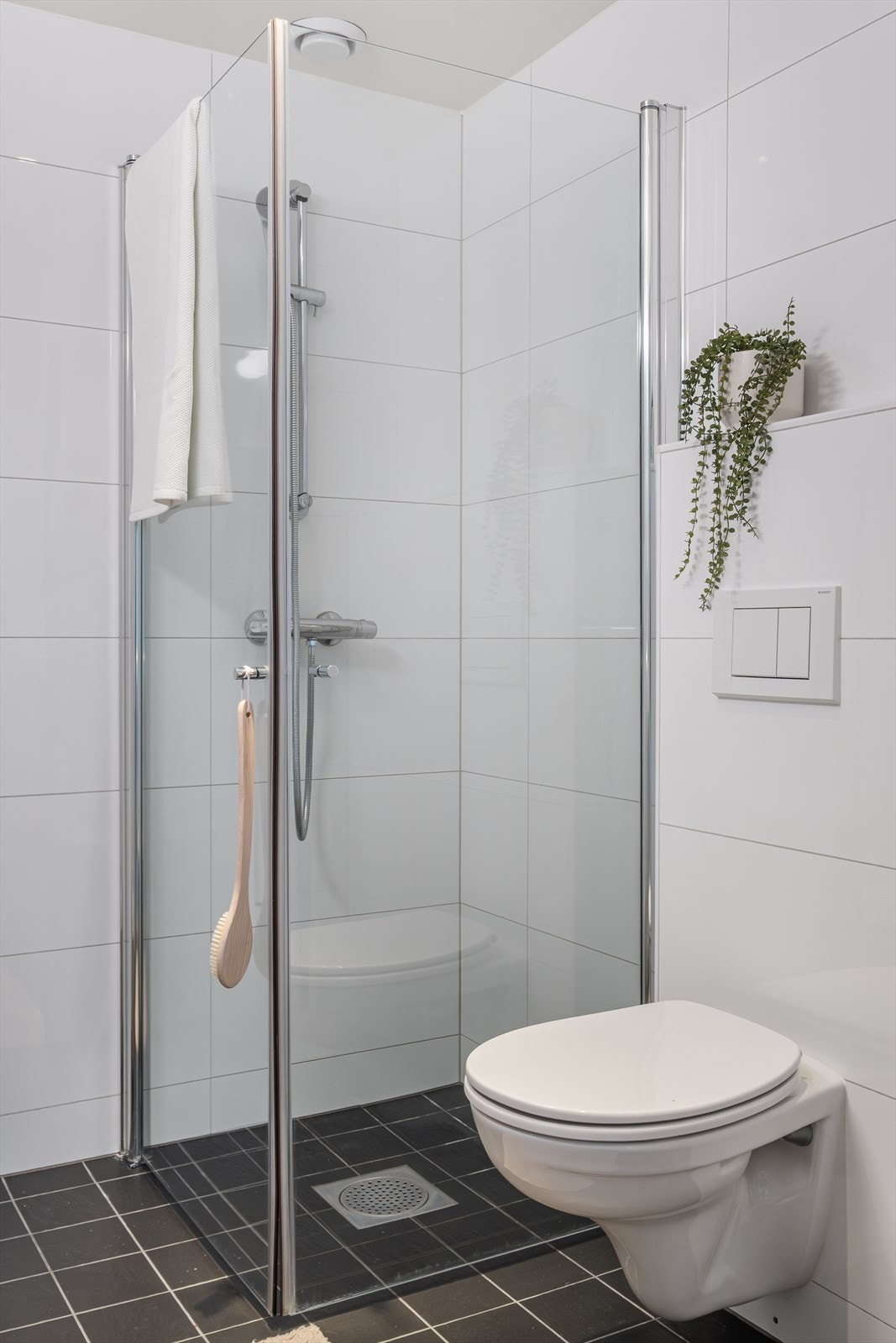 Badet er innredet med speil, armatur, servant med innredning, dusjhjørne med innfellbare glassdører og vegghengt toalett. Galleribilde