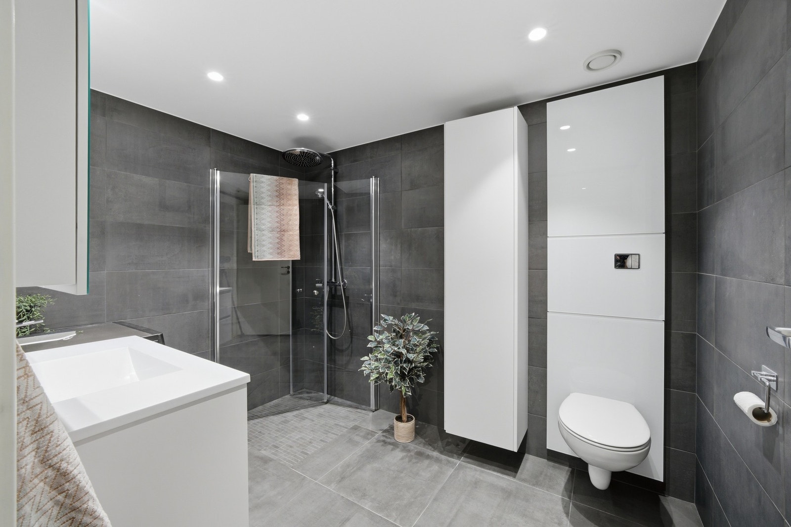 Badet er på ca. 6 kvm og er utstyrt med vegghengt WC, moderne innredning og dusjhjørne med innfellbare dører. Galleribilde