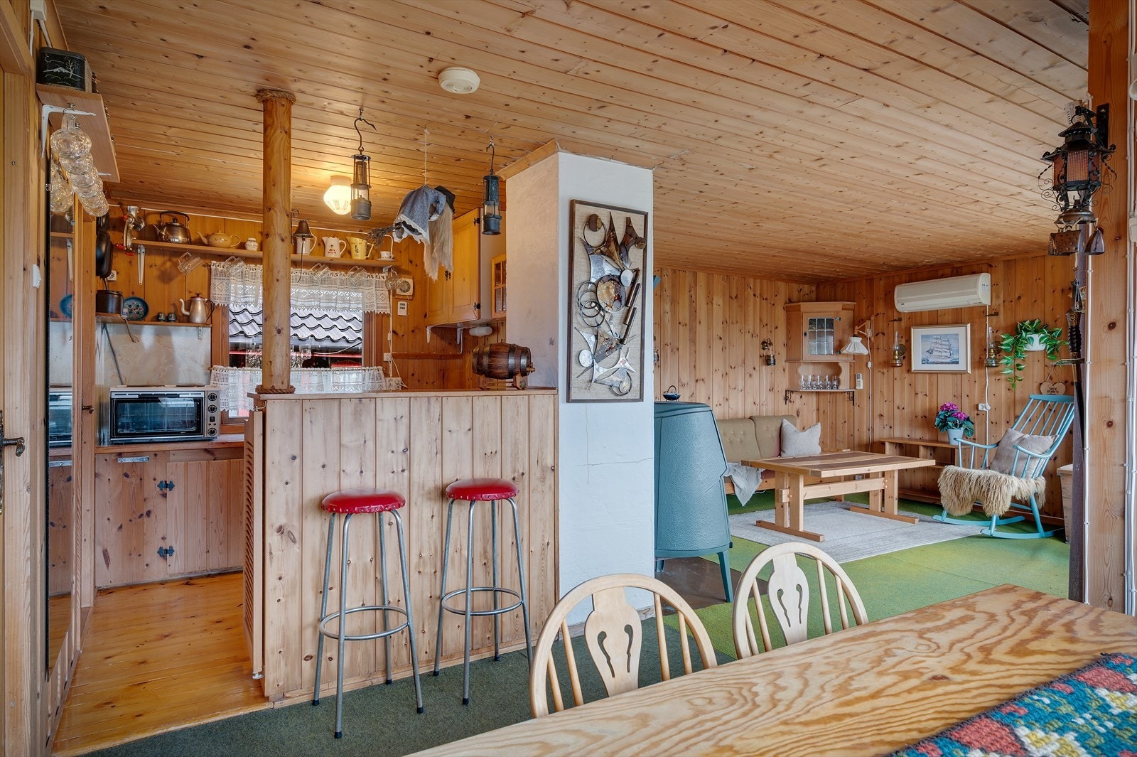 Stue og kjøkken ligger i åpen løsning, og gulvene er dekket med vegg-til-vegg-teppe som forsterker den varme hyttefølelsen. Galleribilde