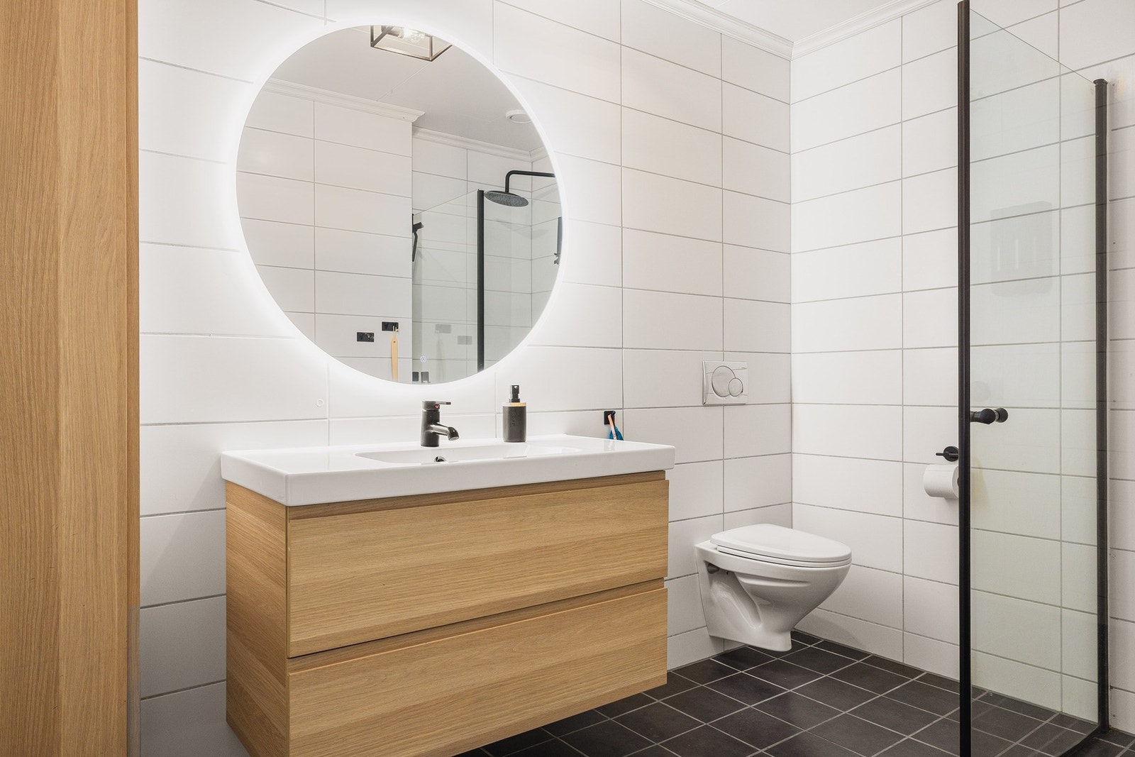 Helfliset bad med dusj med glassvegger, vegghengt toalett og moderne baderomsinnredning. Galleribilde