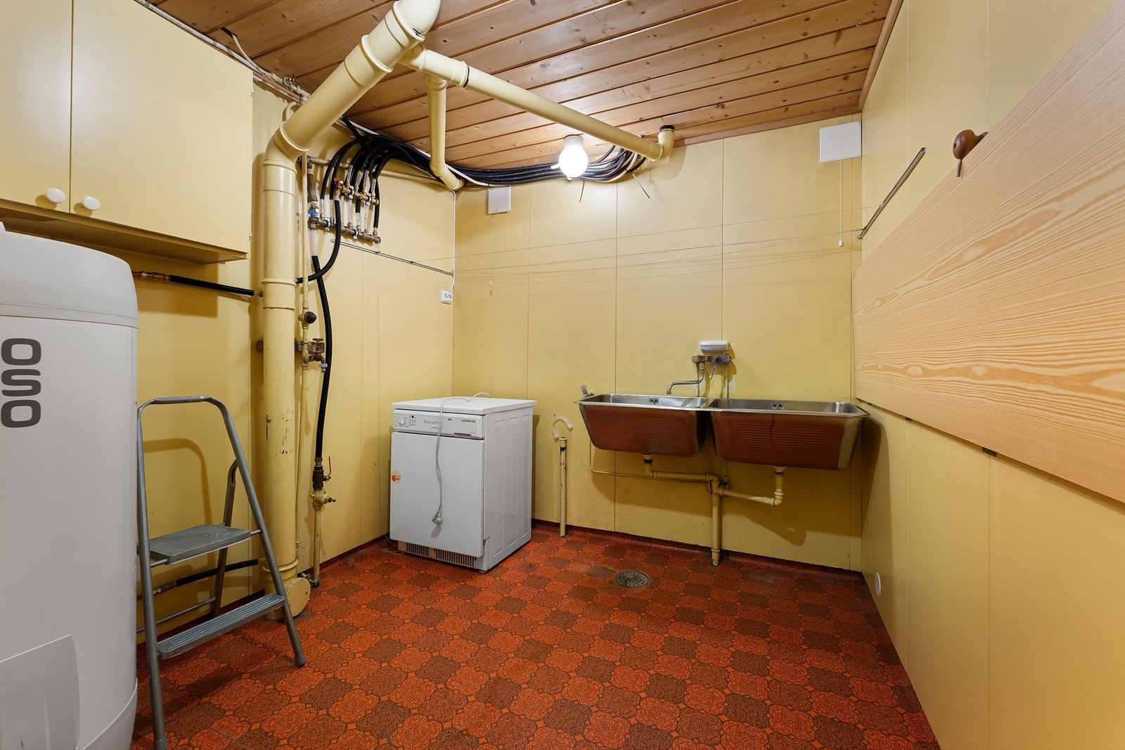 Praktisk vaskerom med utslagsvask, opplegg for vaskemaskin og plassering av varmtvannsbereder. Galleribilde