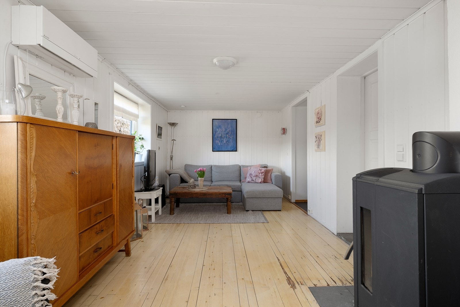Stuen i utleieleiligheten er lys og trivelig, med tregulv og panel på veggene. Luftveksler montert på veggen. Galleribilde