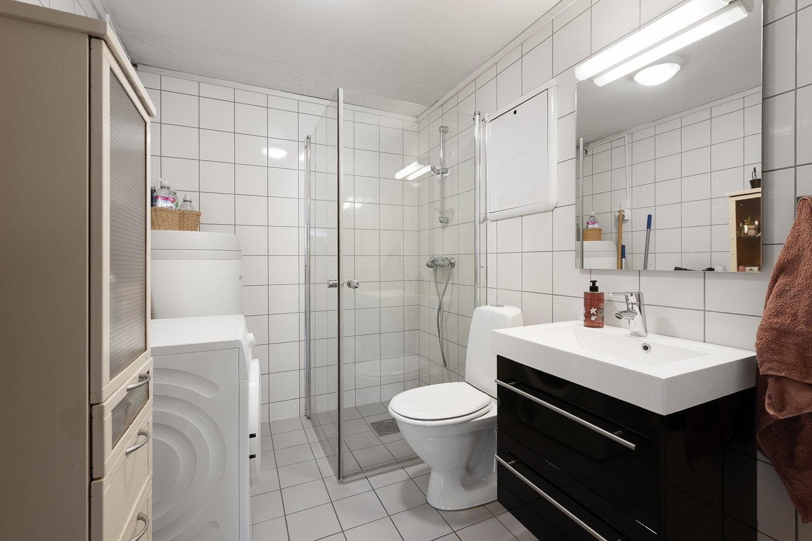 Badet i utleieleiligheten er fra 2011, med fliser på gulv og vegger, gulvvarme, WC, baderomsinnredning og dusjdører i herdet glass. Galleribilde