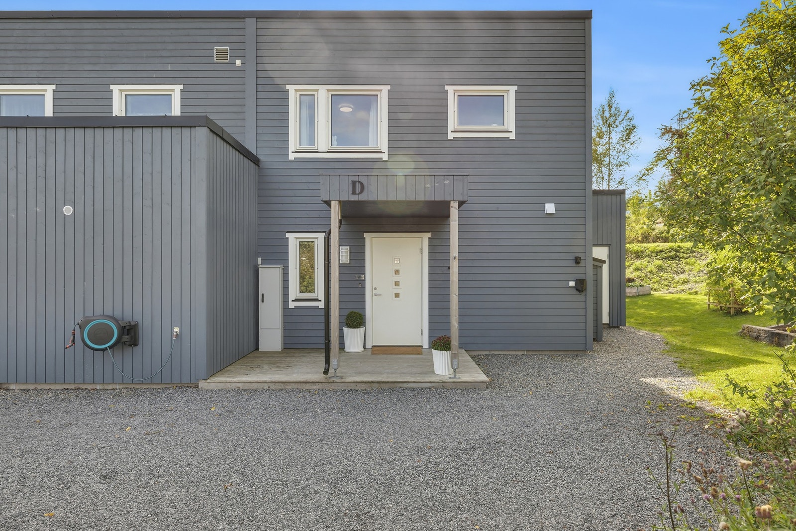 Pent og ryddig inngangsparti med utvendig bod til høyre. Parkeringsplass med EL-billader. Boligen har også en innvendig bod/teknisk rom i 2. etasje. Galleribilde