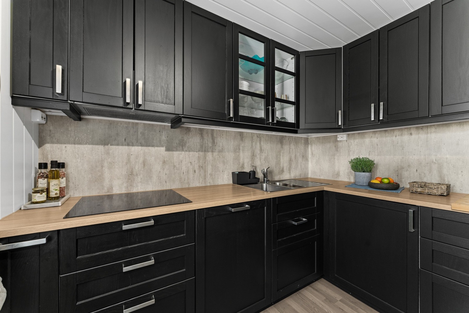 Kitchenboard mellom benkeplate og overskap. Et glasskap med lys. Galleribilde
