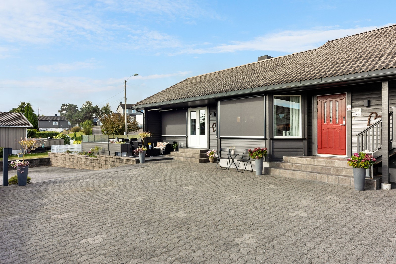 Boligen har en innbydende fasade . Steinlagt gårdsplass skaper et ryddig inntrykk. Galleribilde