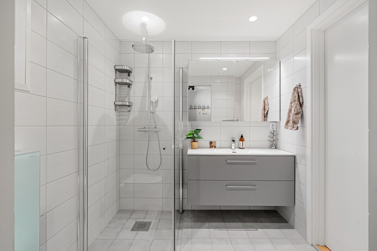 Badet er helfliset og har nedfelt servant i skuffeseksjon. Det er dusjhjørne, vegghengt toalett og adkomst til vaskerom. Galleribilde