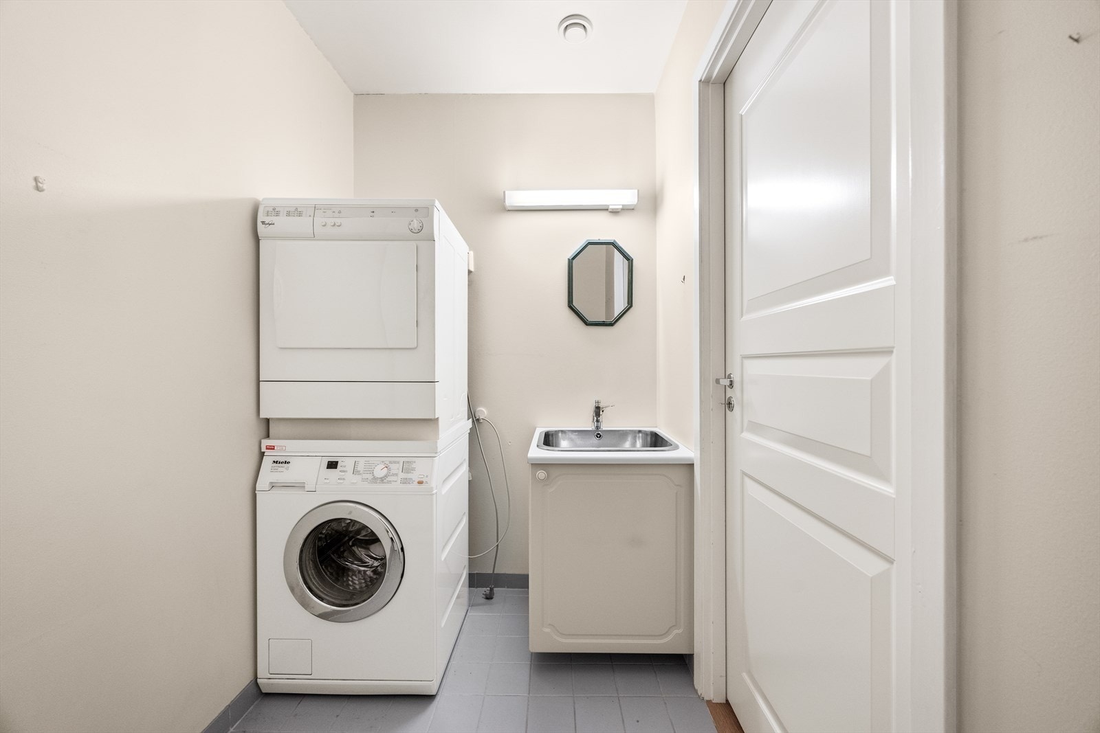 Vegg i vegg med badet ligger vaskerom med opplegg for vaskemaskin, underskap med vask og opplegg til dusj. Galleribilde