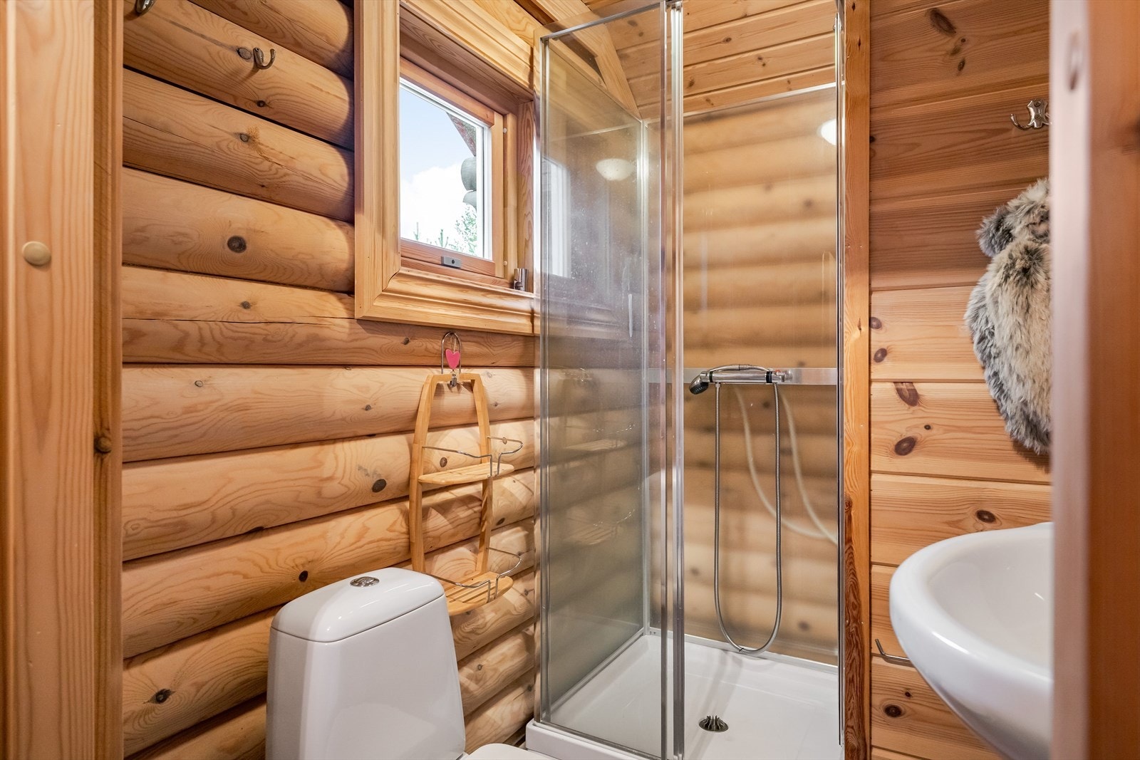 Badet har flislagt gulv med varmekabler og vegger med tømmer og panel. Galleribilde