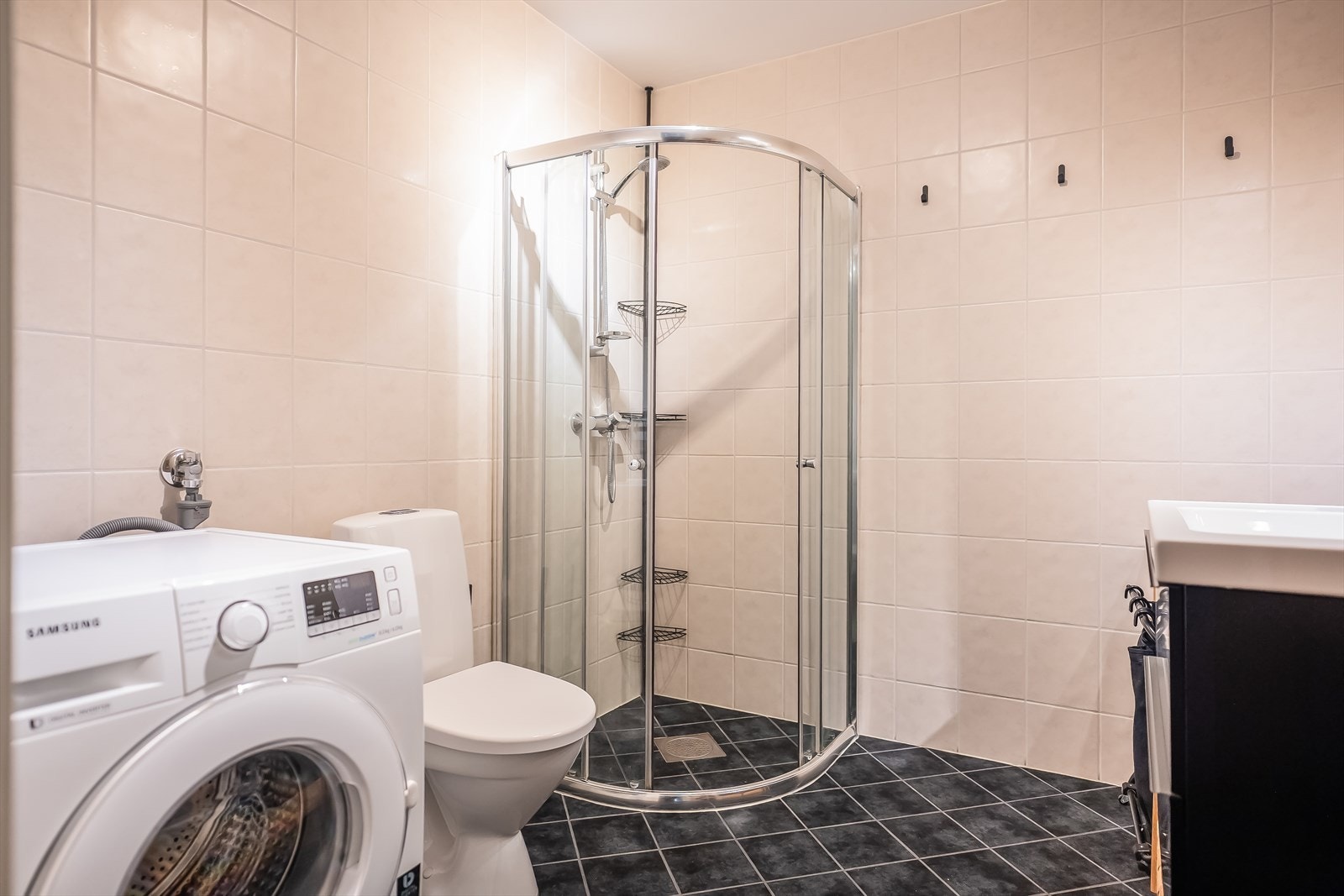 Badet er utstyrt med hjørnedusj, opplegg for vaskemaskin og en romslig servantløsning med gode oppbevaringsmuligheter. Galleribilde