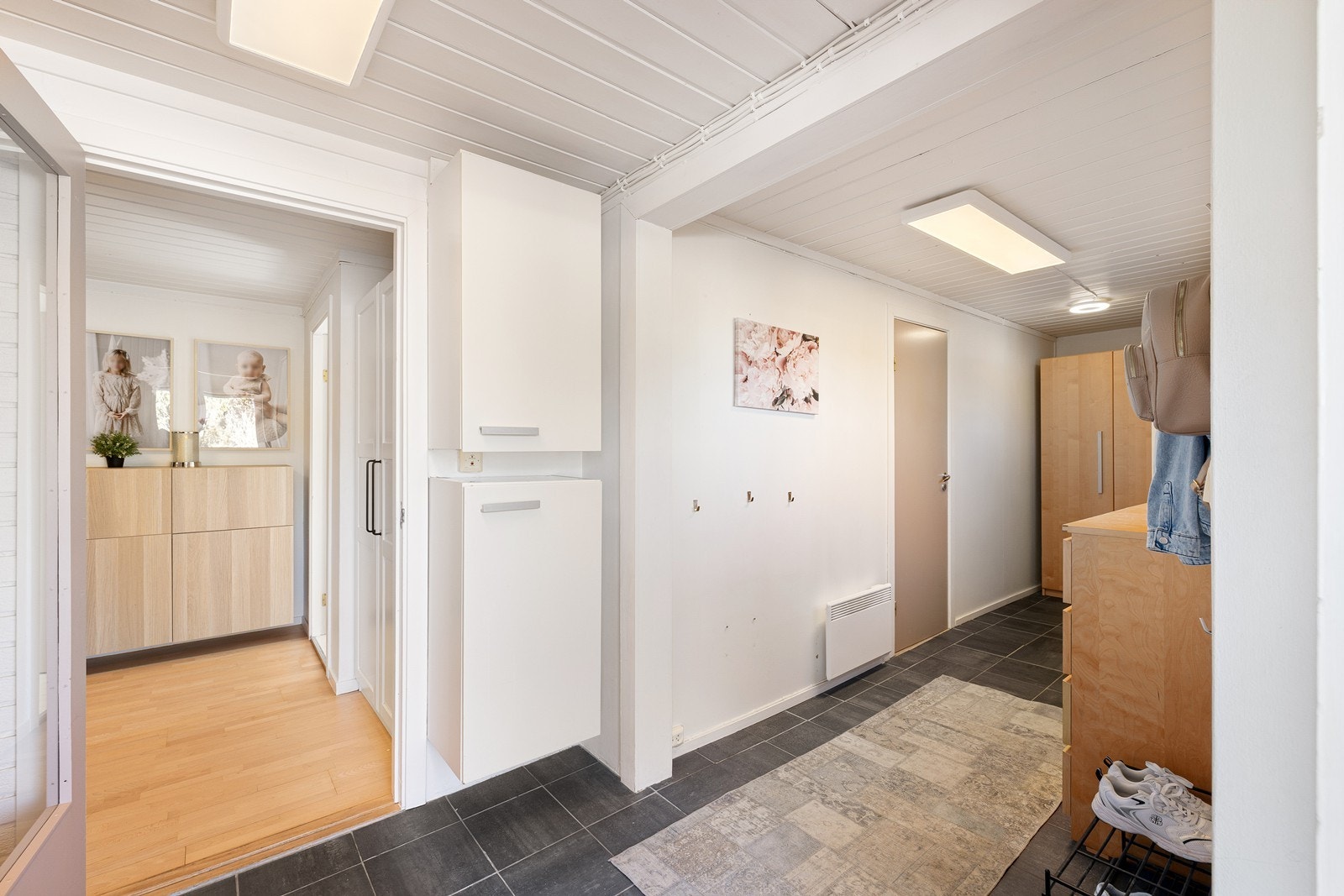 Inne møtes du av en innbydende og romslig entré. Her kombineres det praktiske med det stilfulle, med fliser på gulv, og god plass til yttertøy i garderobeskap. Galleribilde