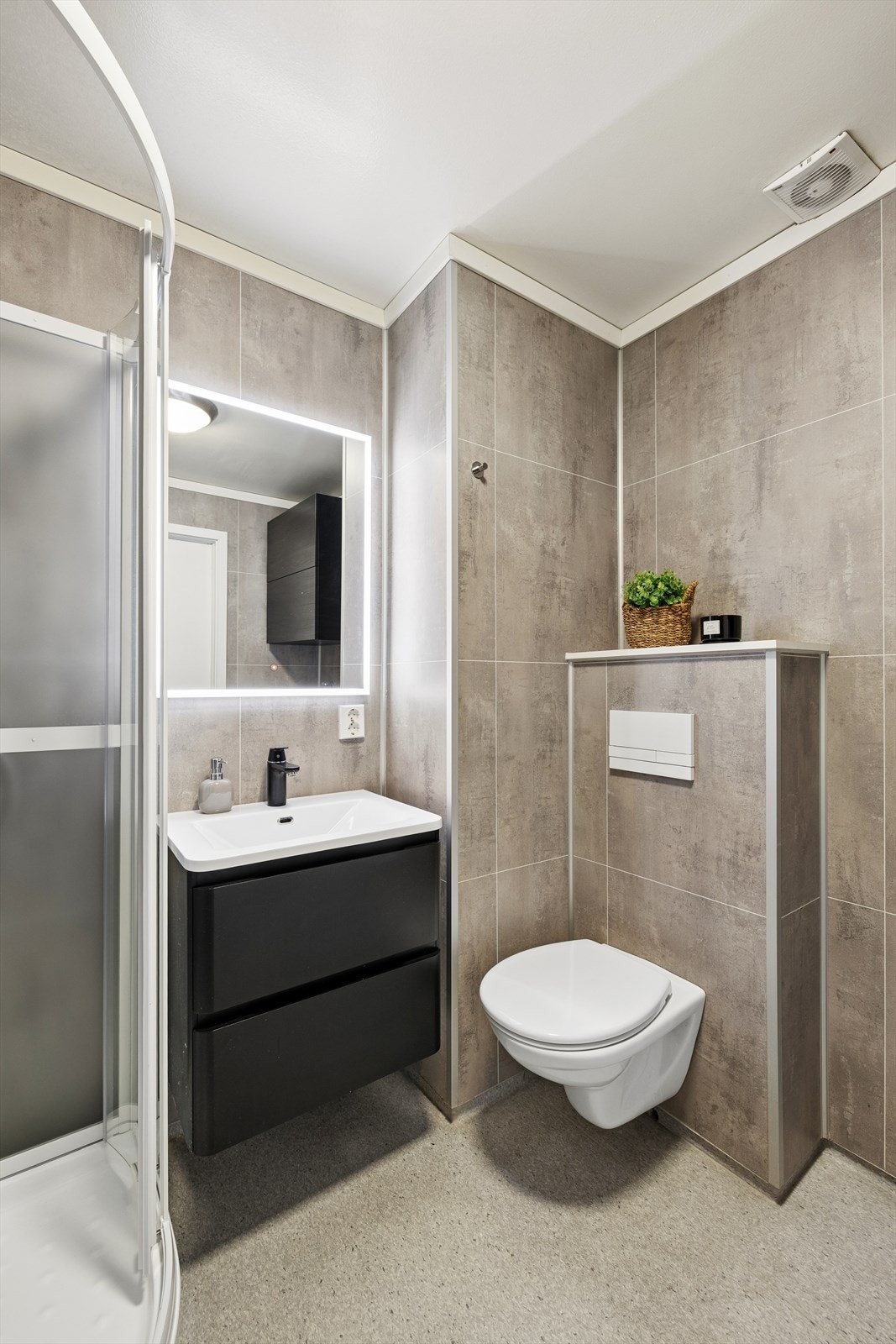 Badet har innredning med nedfelt servant, veggmontert toalett, dusjkabinett (fra 2026) og opplegg for vaskemaskin. Galleribilde