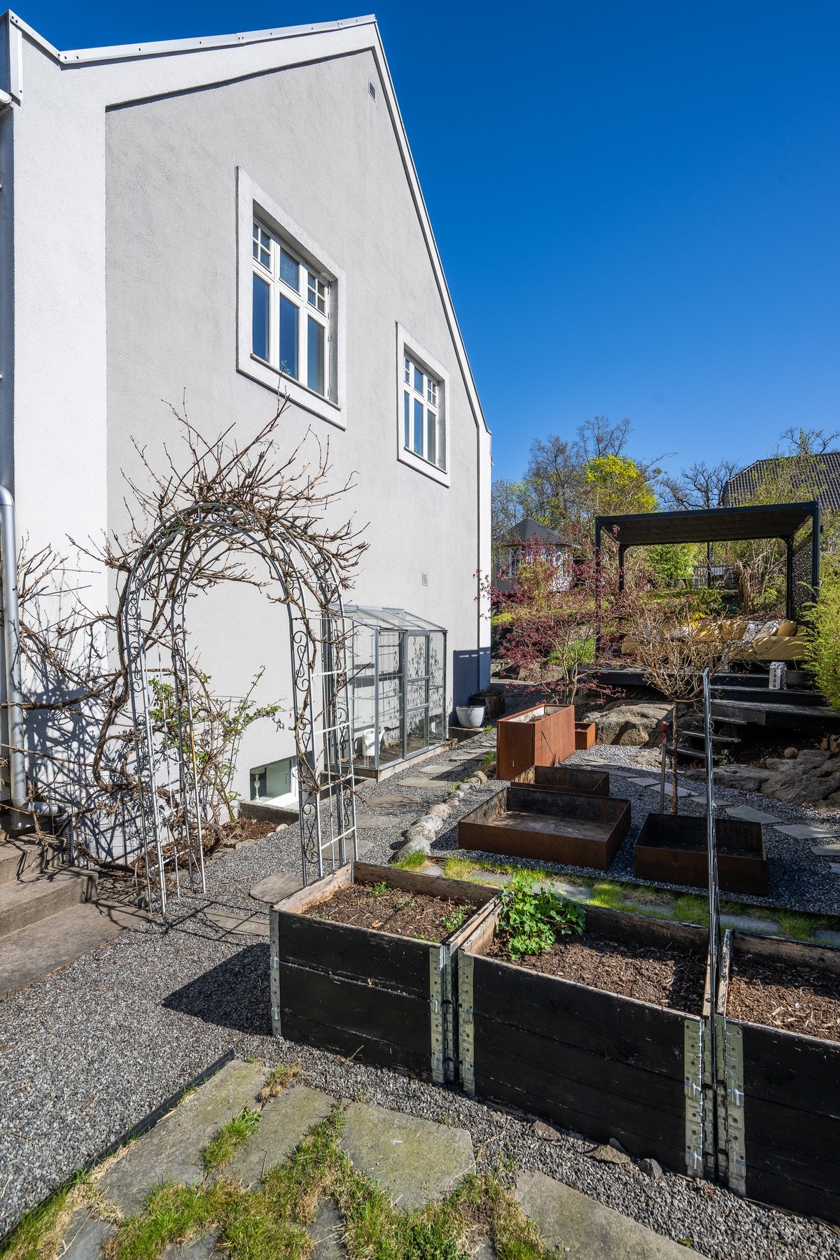 På den frodige tomten er det flere pallekasser som er klare for en ny sesong - minidrivhus inn mot veggen Galleribilde