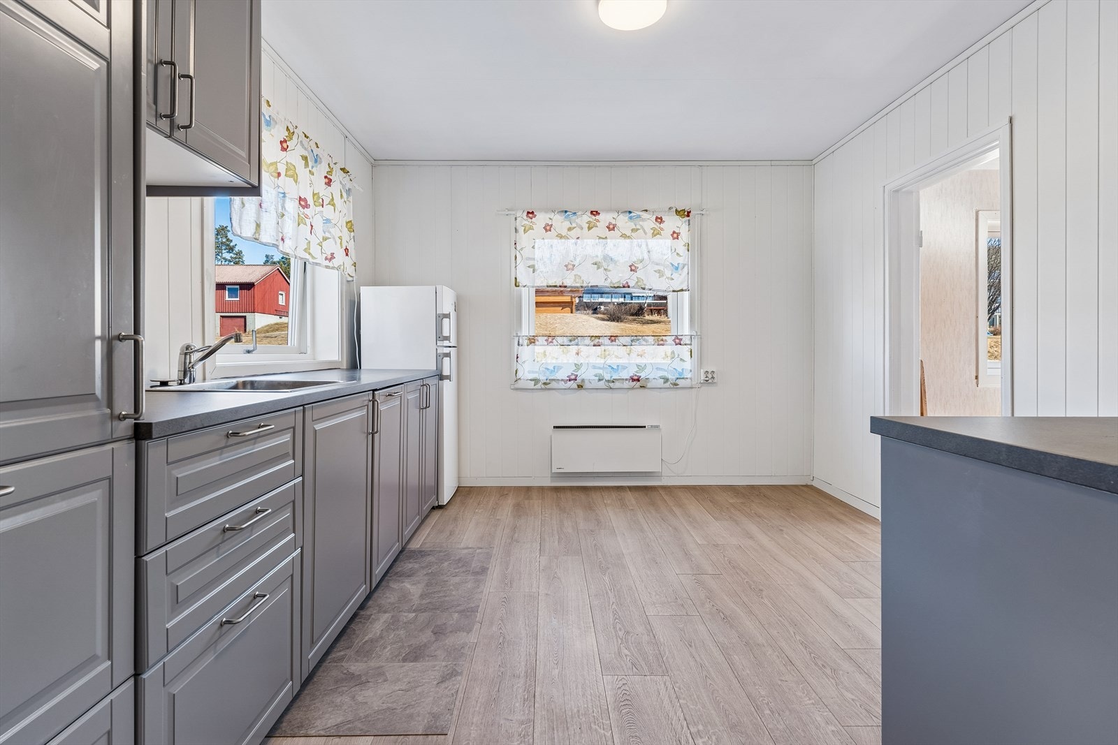 Innredningen har profilerte fronter, laminatbenkeplate med nedfelt vask og kjøkkenventilator med avtrekk ut. Galleribilde