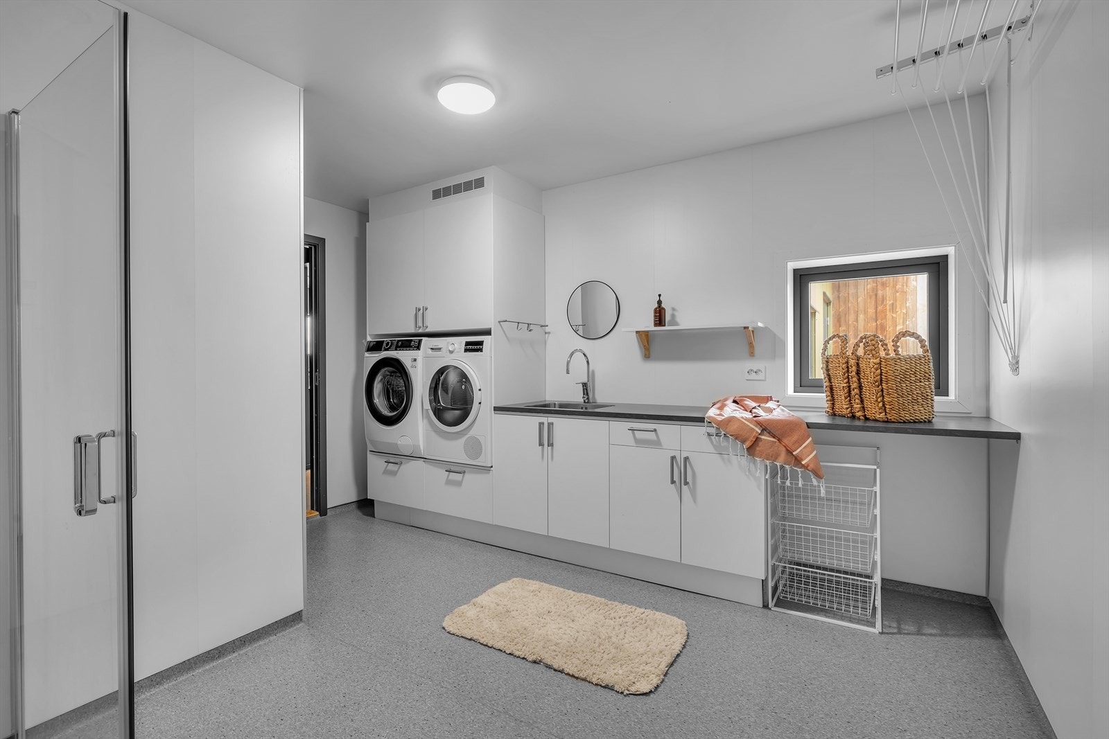 Romslig vaskerom med innredning, benkeplate og utslagsvask. Dette rommet har også dusj Galleribilde