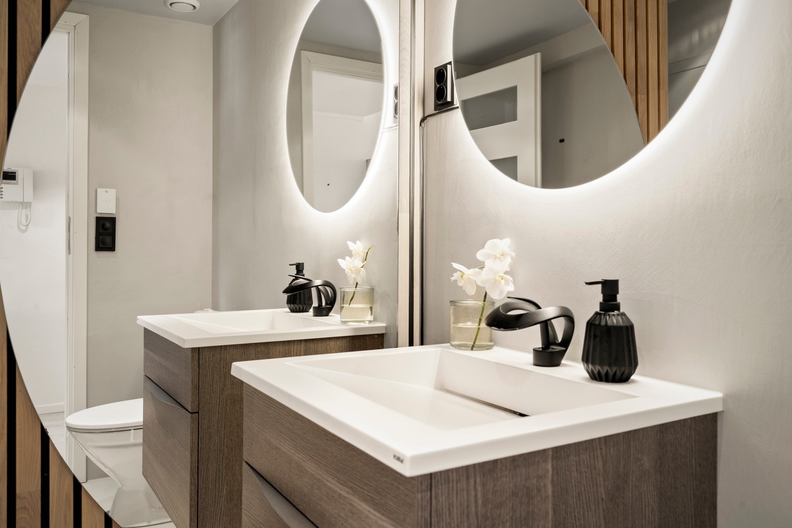 Badet har et stilfullt og moderne uttrykk, blant annet gjennom spilevegg mellom dusjsone og servantinnredning, med integrert belysning og halvmåneformet speil. Galleribilde