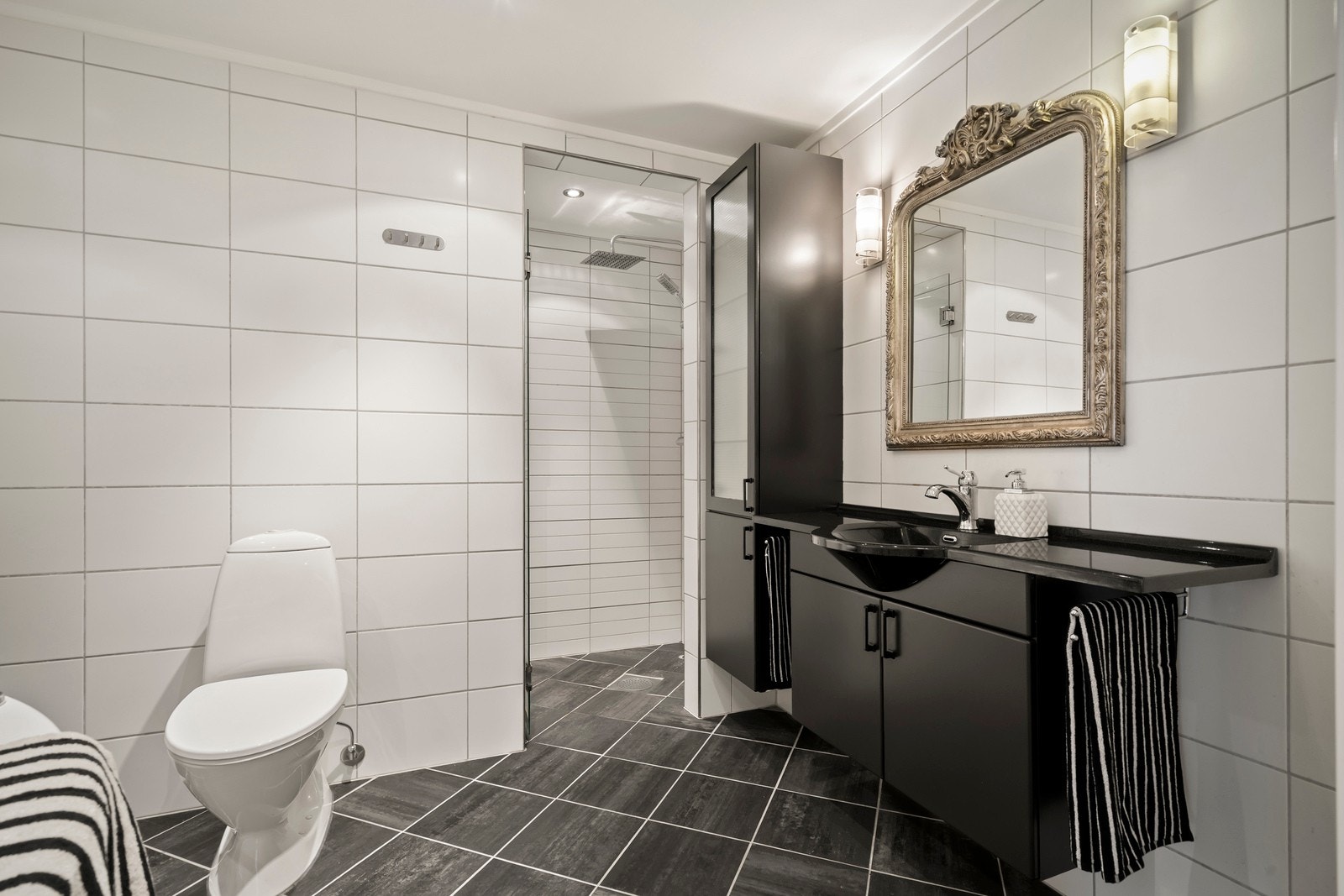 Romslig hovedbad med flislagte gulv- og veggflater. Badet er utstyrt med vannbåren gulvvarme og innfelte downlights i himling med malte plater. Galleribilde