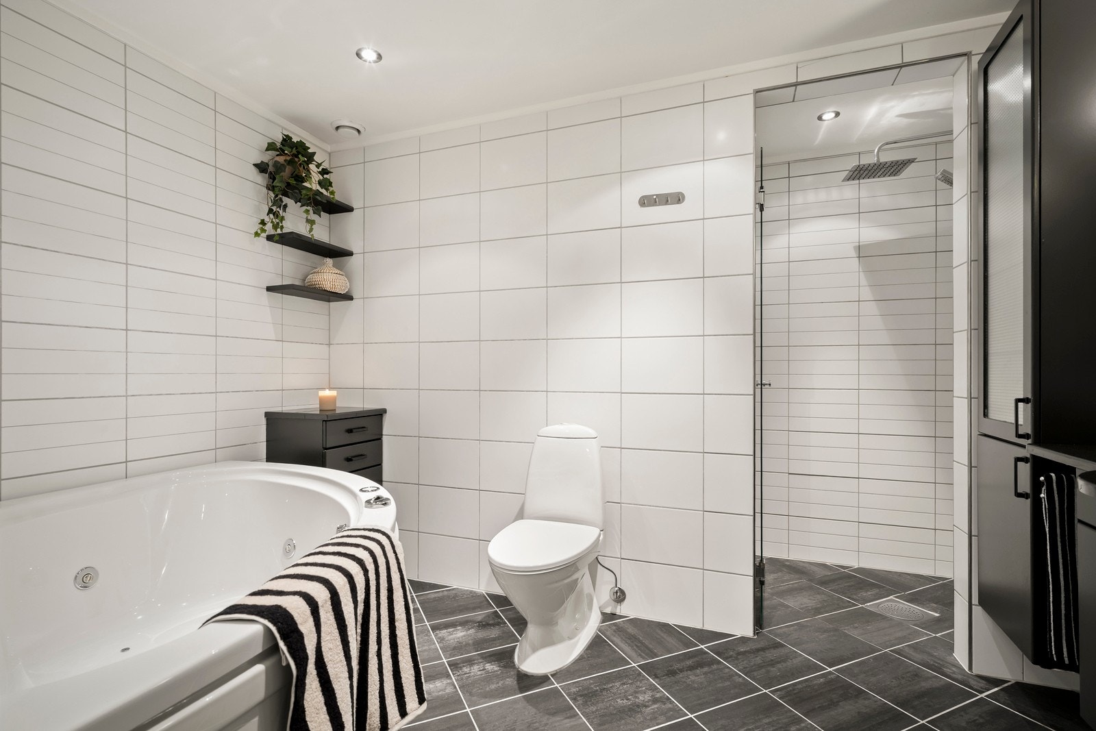 Badet er blant annet utstyrt med gulvstående klosett, dusjnisje med svingbar glassdør samt servantinnredning og et praktisk vegghengt skap. Galleribilde