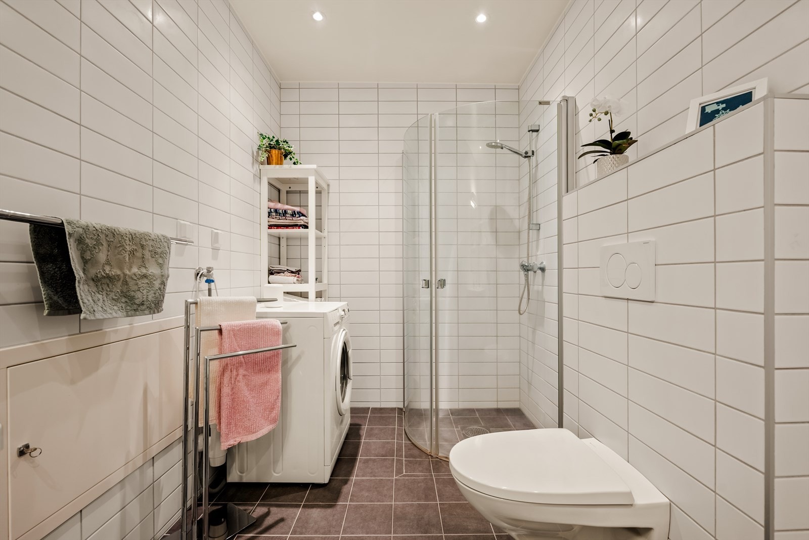 Badet er utstyrt med en dusjnisje med glassdører, vegghengt toalett og en servantinnredning. Her er det også opplegg for vaskemaskin. Galleribilde