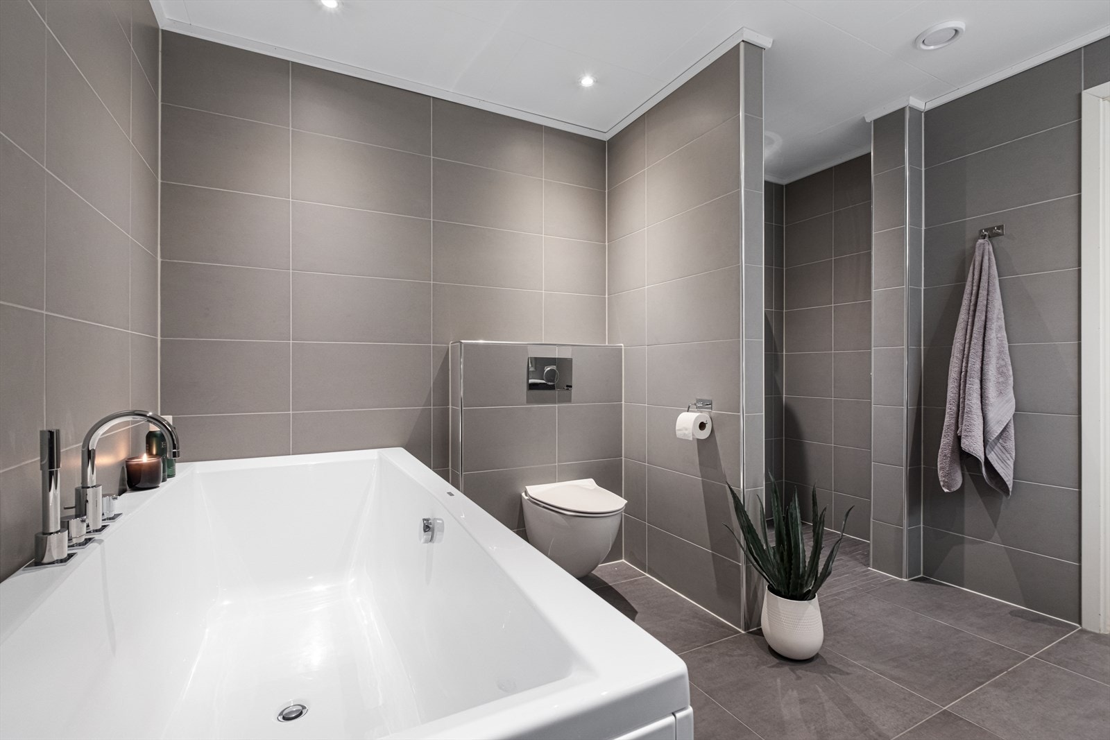 Badet er utstyrt med vegghengt toalett og et stort badekar. Galleribilde