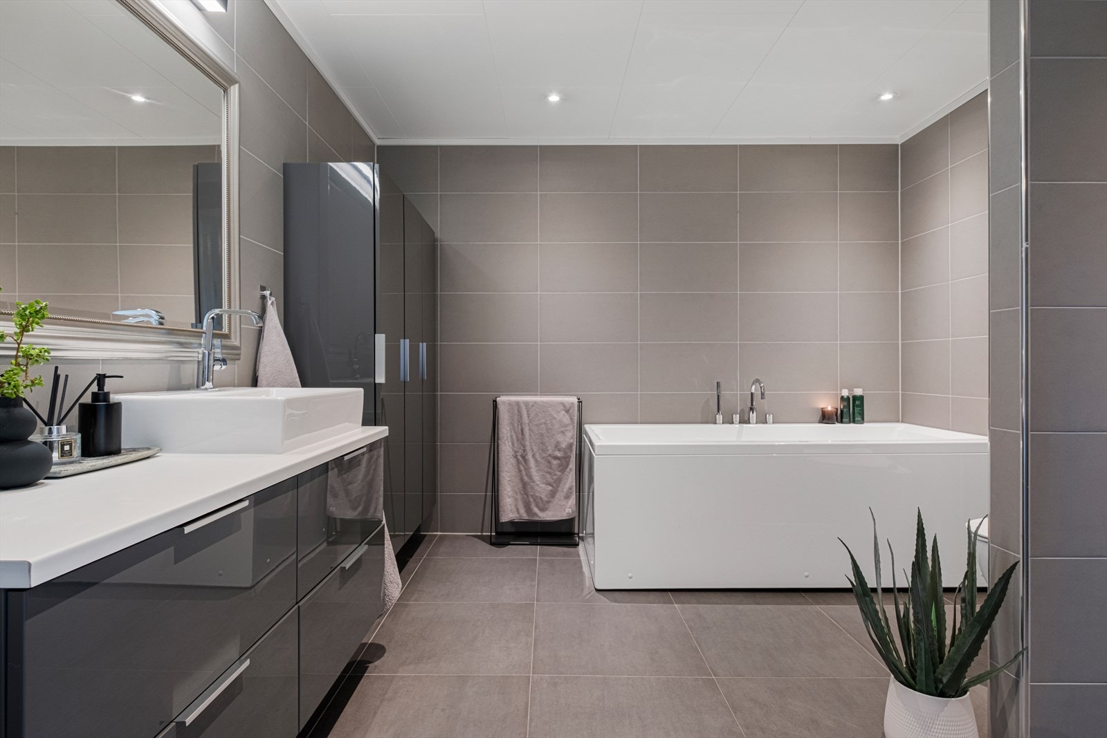 Badet inkluderer et romslig badekar og flislagte vegger med nøytrale toner. Galleribilde