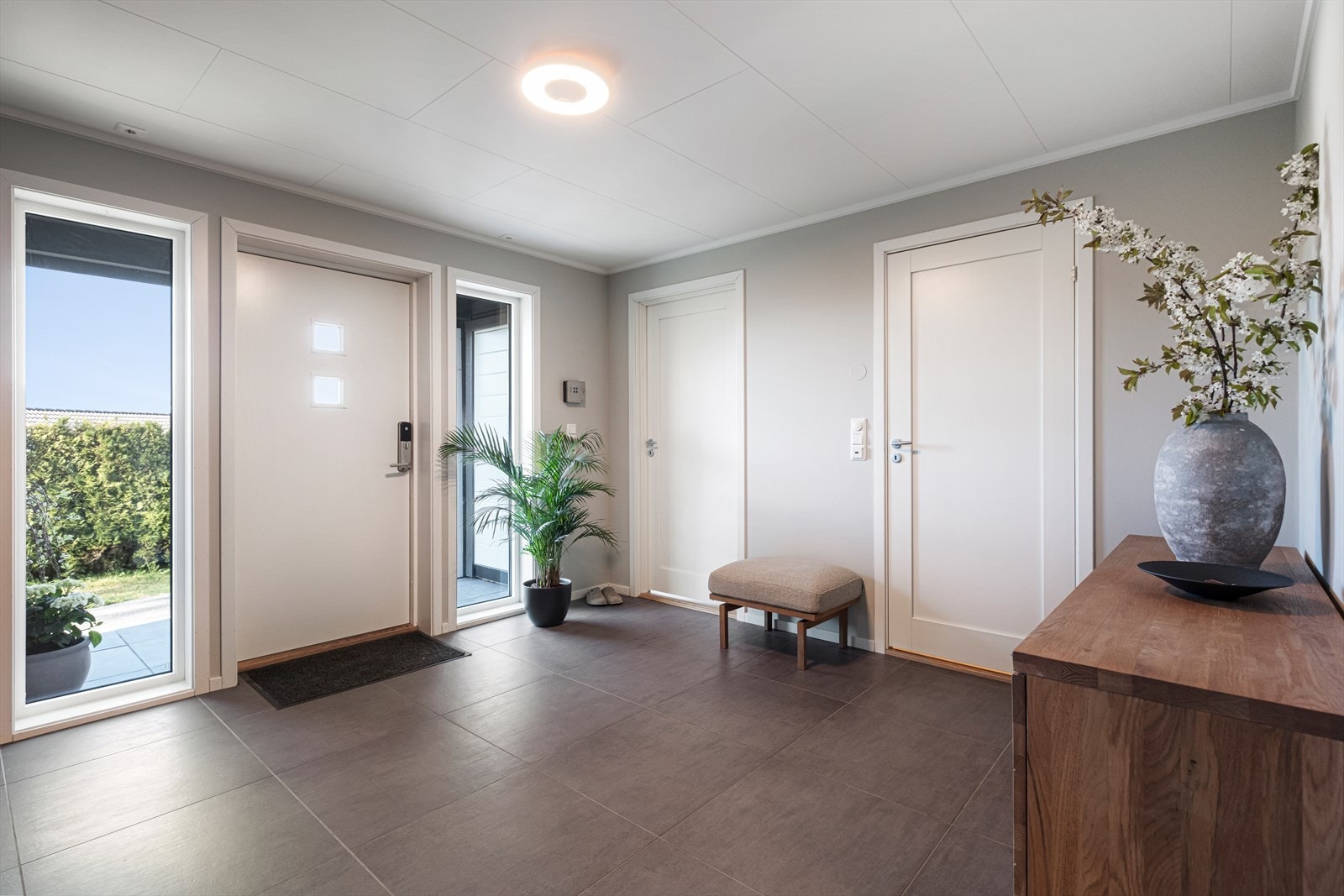 Entréen har direkte utgang til utendørsområdet gjennom en lys hoveddør. Galleribilde