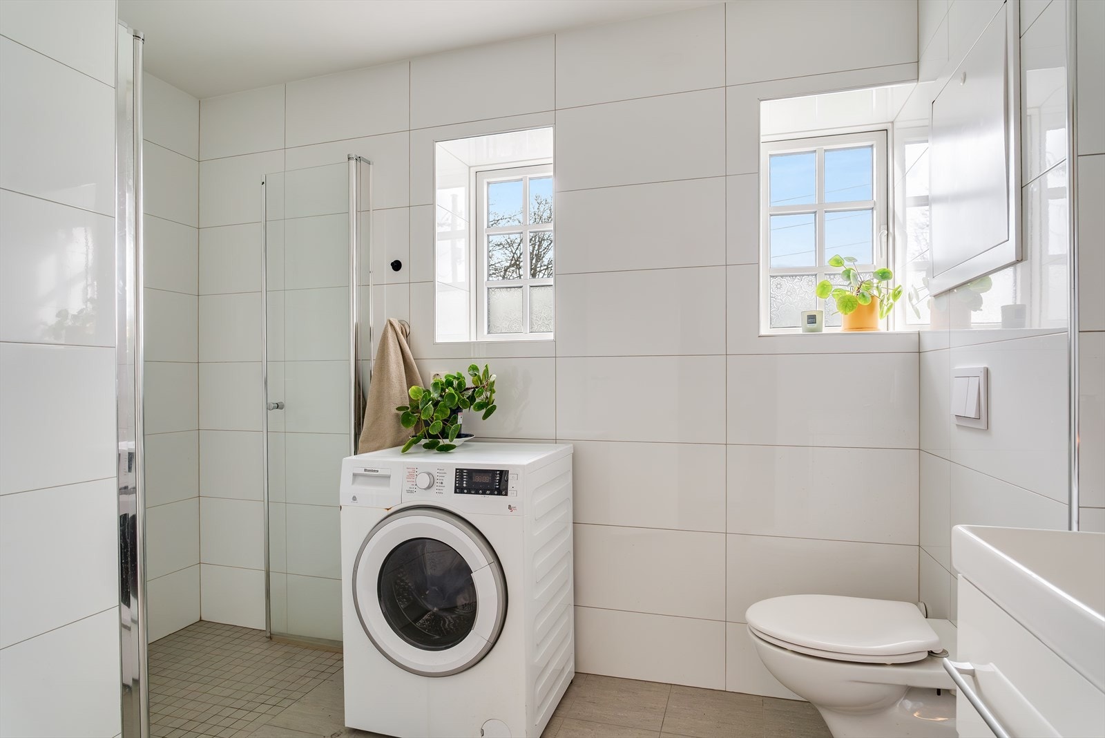 Badet har flislagte overflater, dusjnisje og opplegg for vaskemaskin. Galleribilde