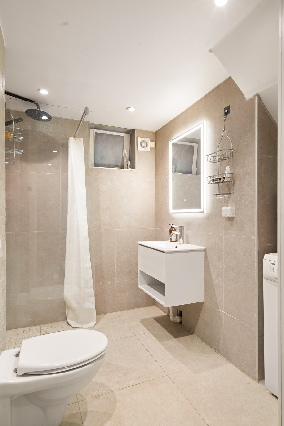 Badet i kjelleren har innredning med nedfelt servant, veggmontert toalett, dusjvegger/hjørne og opplegg for vaskemaskin. Galleribilde