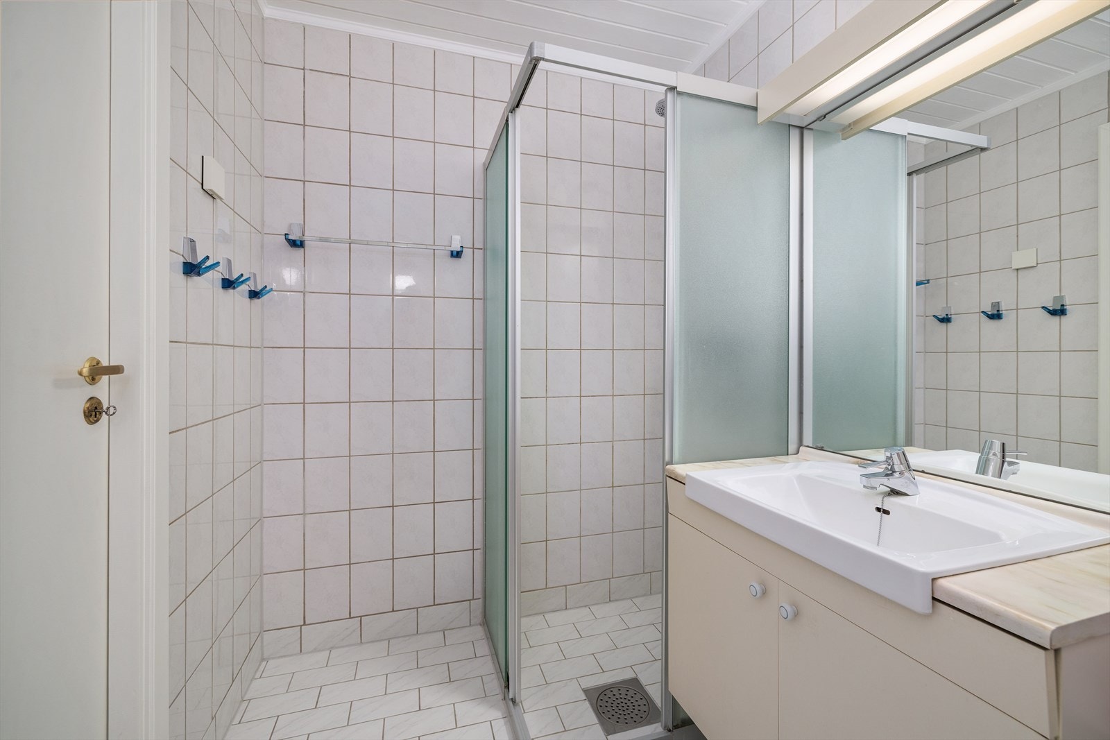 Badet er flislagt og utstyrt med dusjhjørne med skyvedører, servantinnredning og speilbelysning. Galleribilde