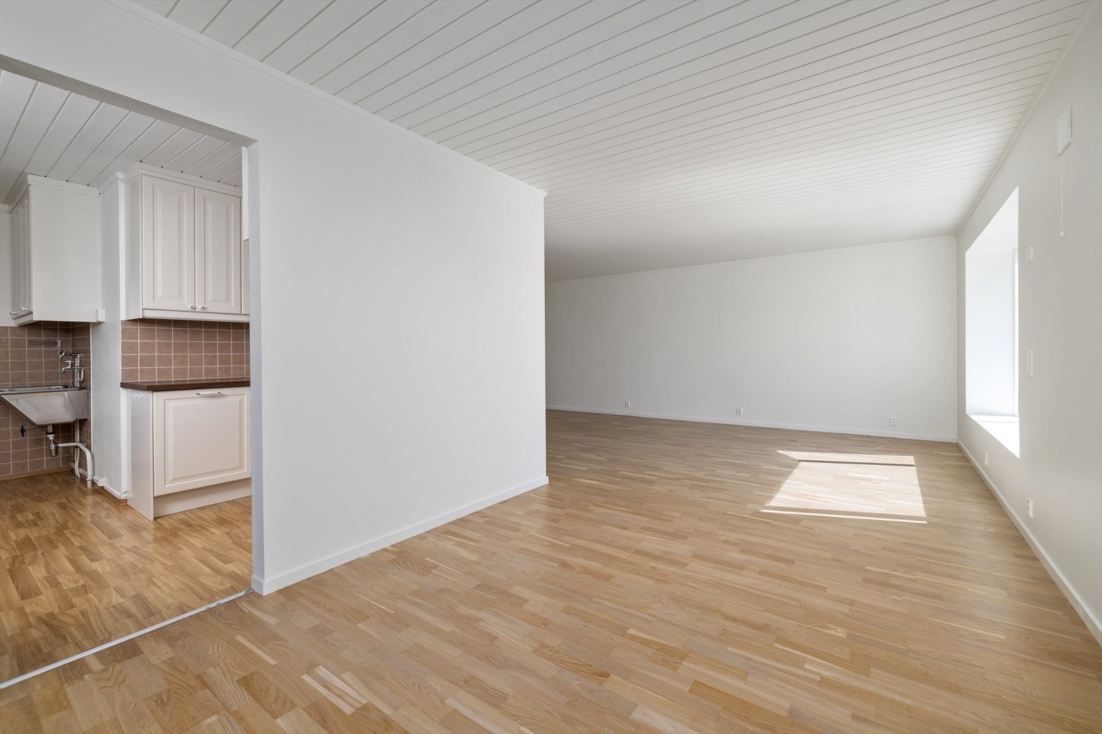 Stuen ligger i delvis åpen løsning mot kjøkkenet, med parkett på gulvet og panel i taket. Galleribilde