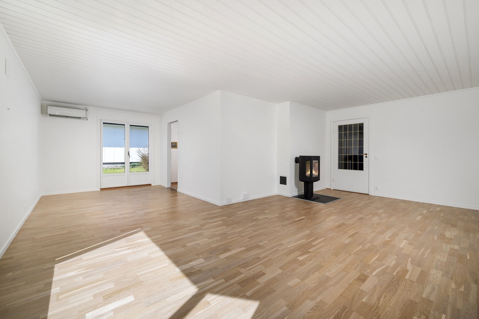 Den romslige stuen har plass til både sofagruppe og spisebord, og et ildsted med glassdør gir ekstra varme og hygge. Galleribilde