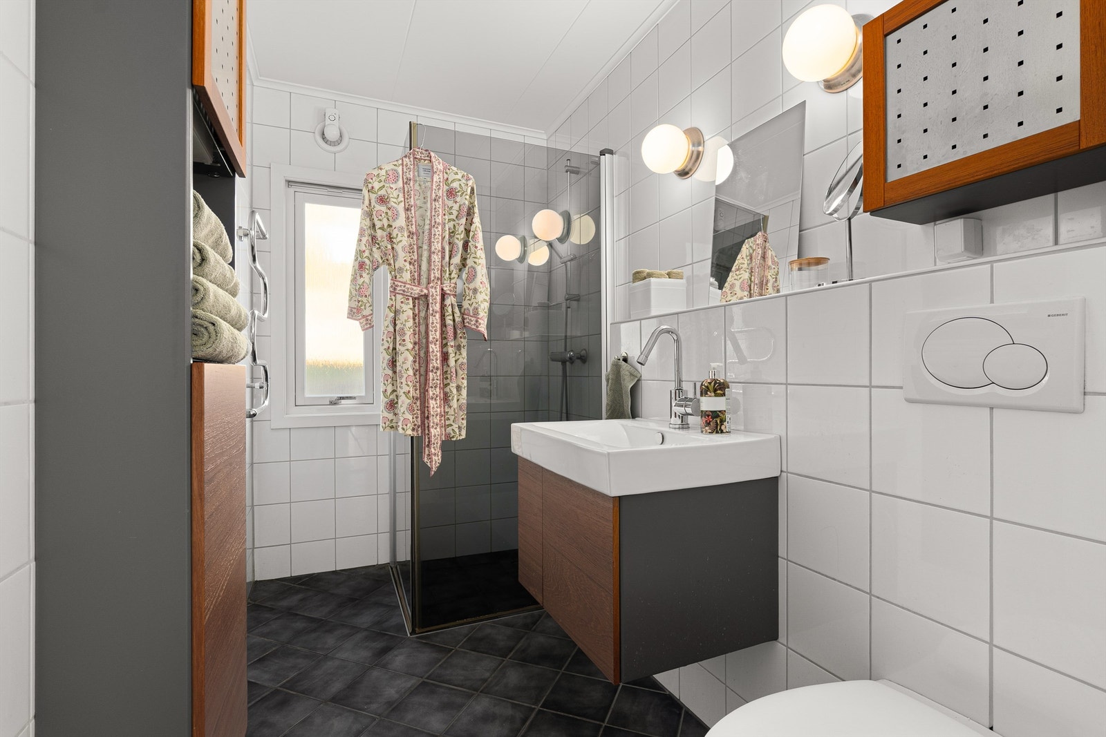 Pent og funksjonelt bad med dusjløsning, moderne innredning og flislagte overflater. Godt med oppbevaringsplass og praktiske løsninger. Galleribilde